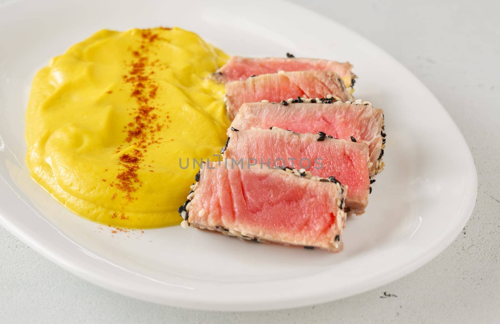 Crisp sesame tuna rests beside smooth cauliflower curry, balanced and visually refined
