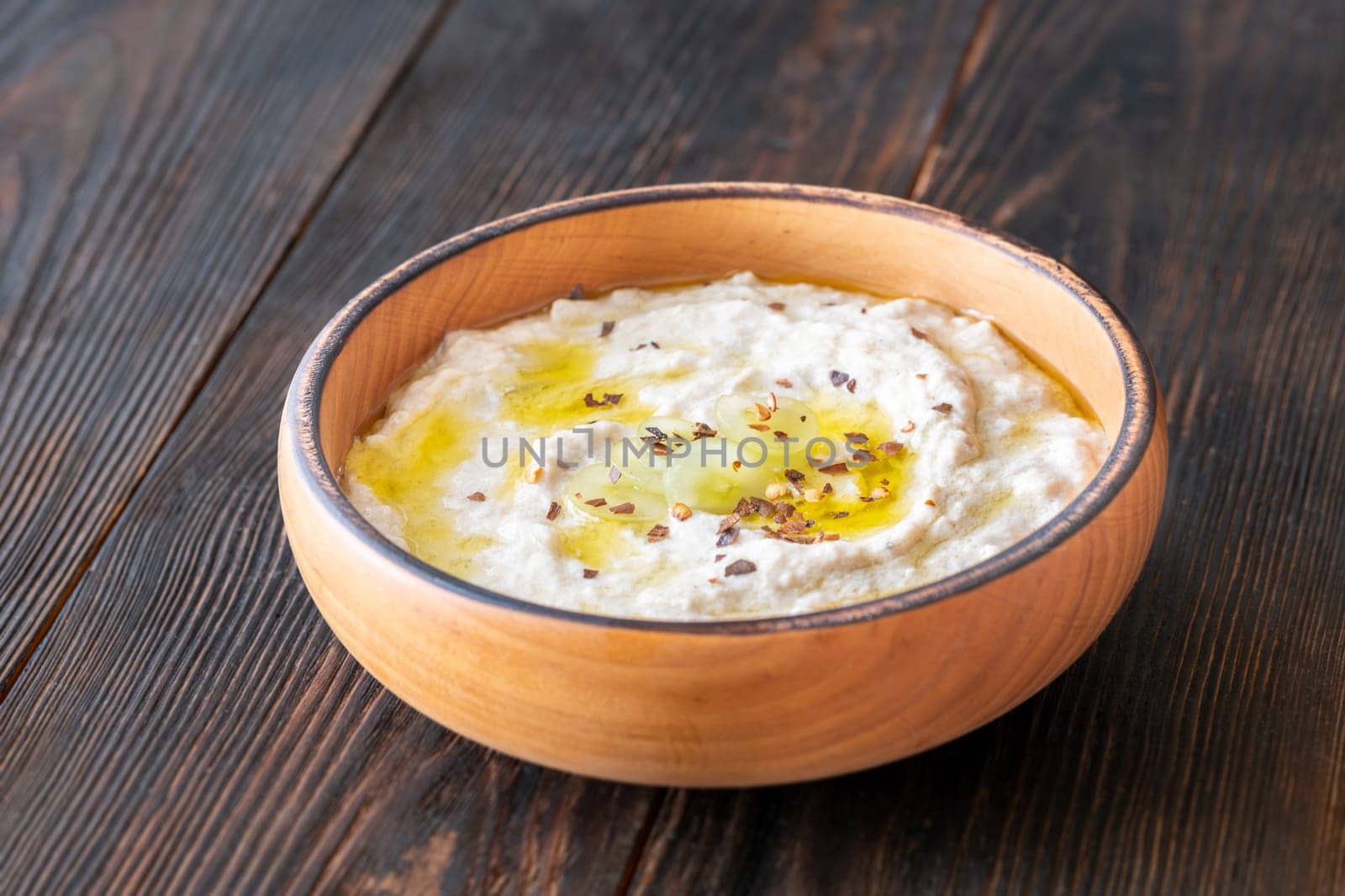 Roasted eggplant dip topped with chili flakes and oil in rustic setting