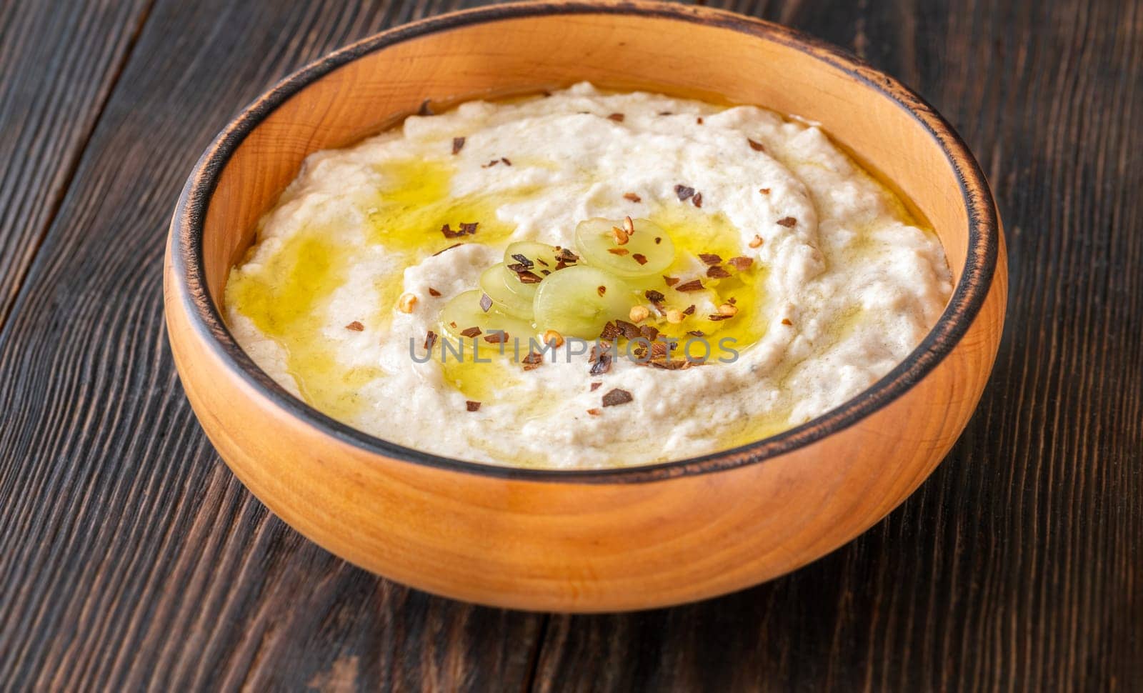 Roasted eggplant dip topped with chili flakes and oil in rustic setting