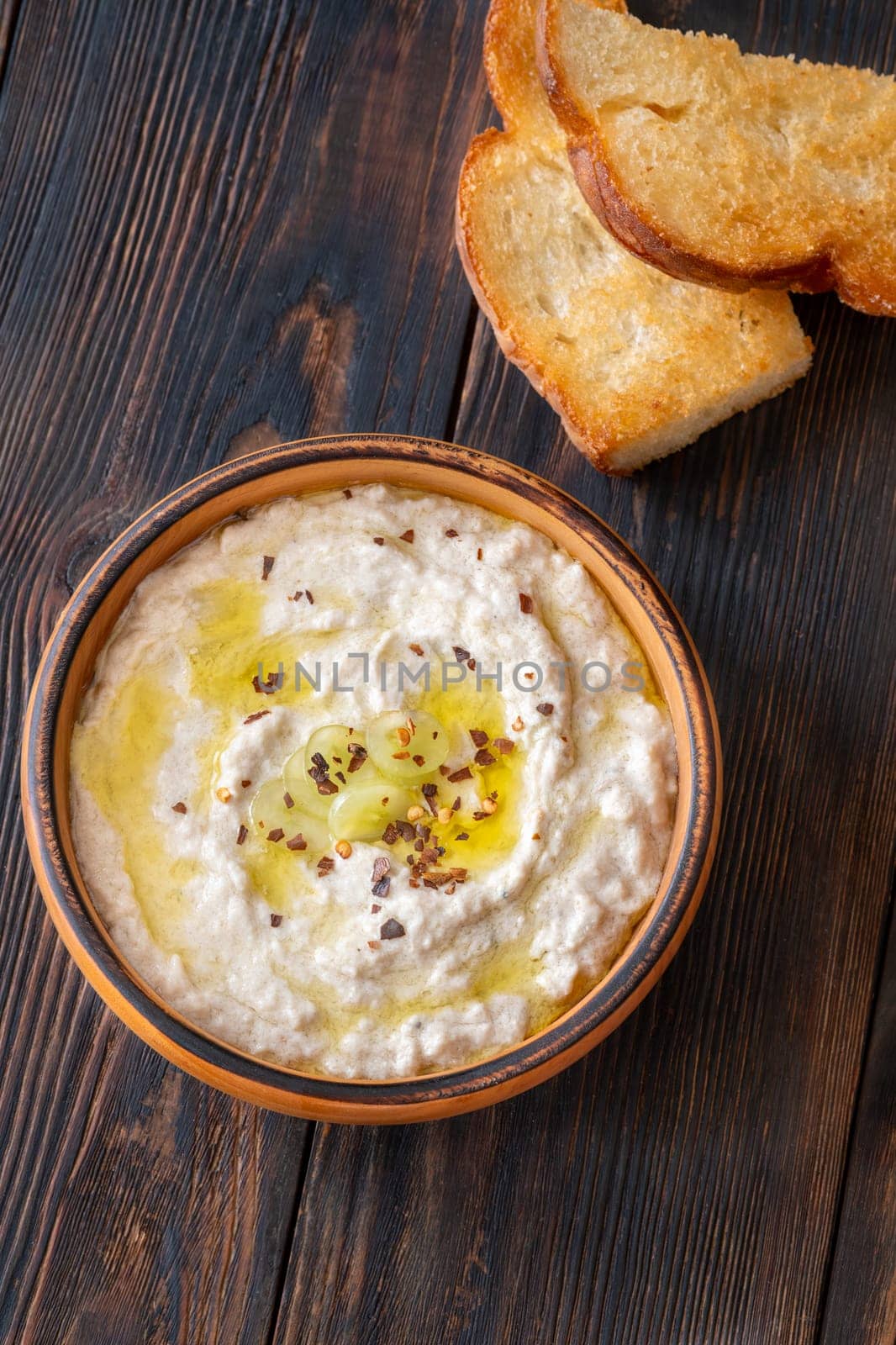Roasted eggplant dip topped with chili flakes and oil in rustic setting