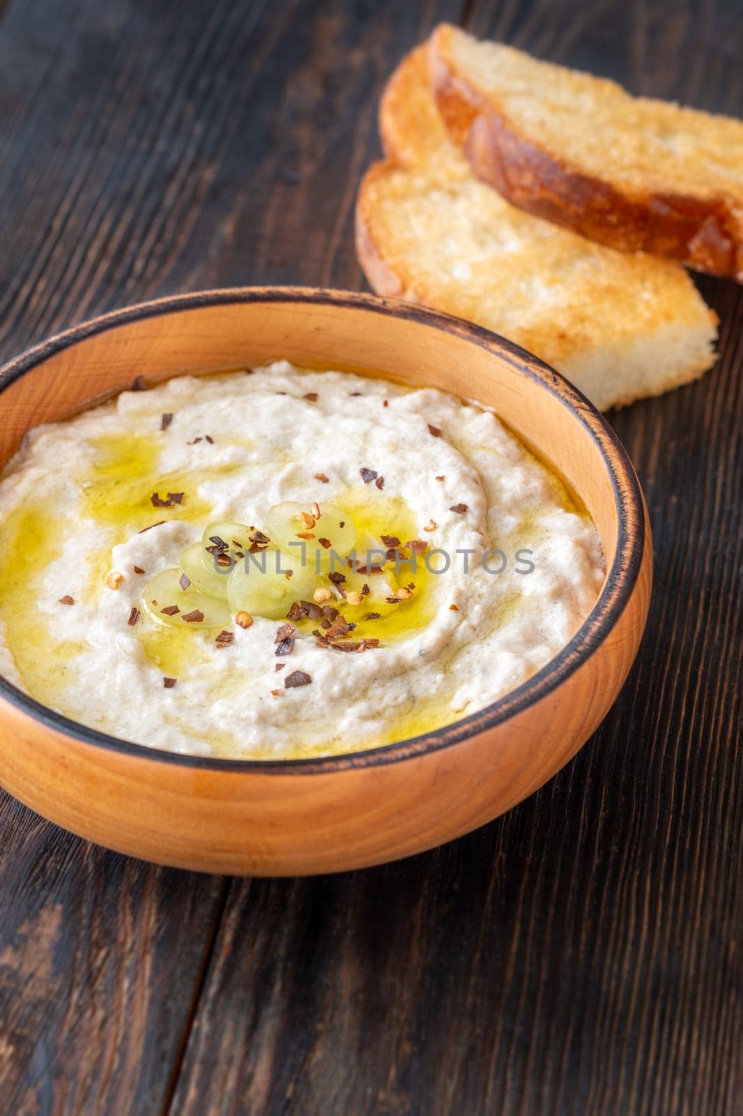 Roasted eggplant dip topped with chili flakes and oil in rustic setting