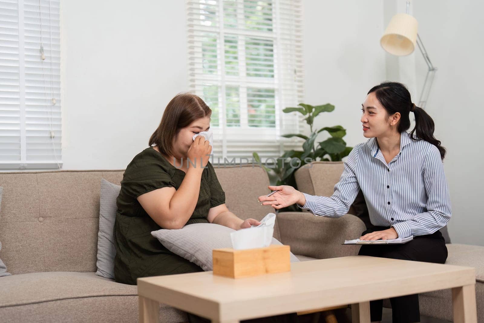 An understanding psychiatrist helps her patient navigate through tears, facilitating an open discussion surrounding difficult emotions and experiences in therapy.