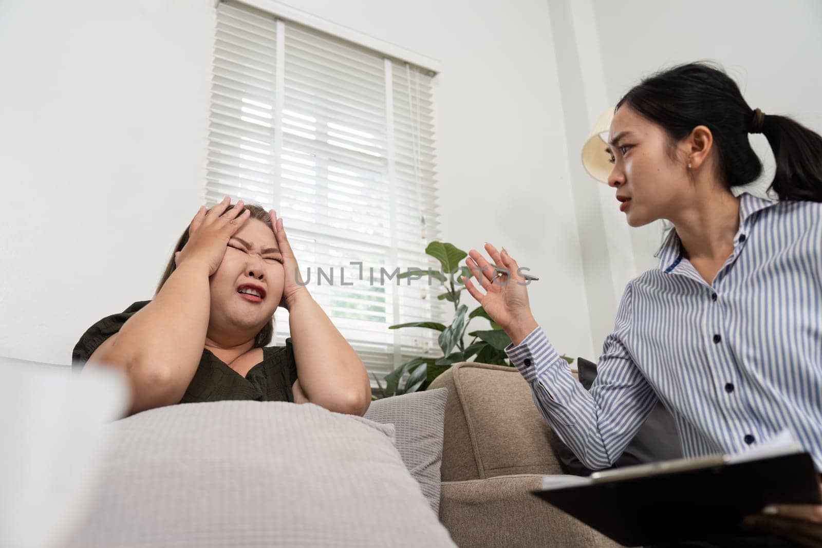 A psychiatrist listens intently as her patient expresses distress, demonstrating empathy while navigating through emotional issues during a counseling session.