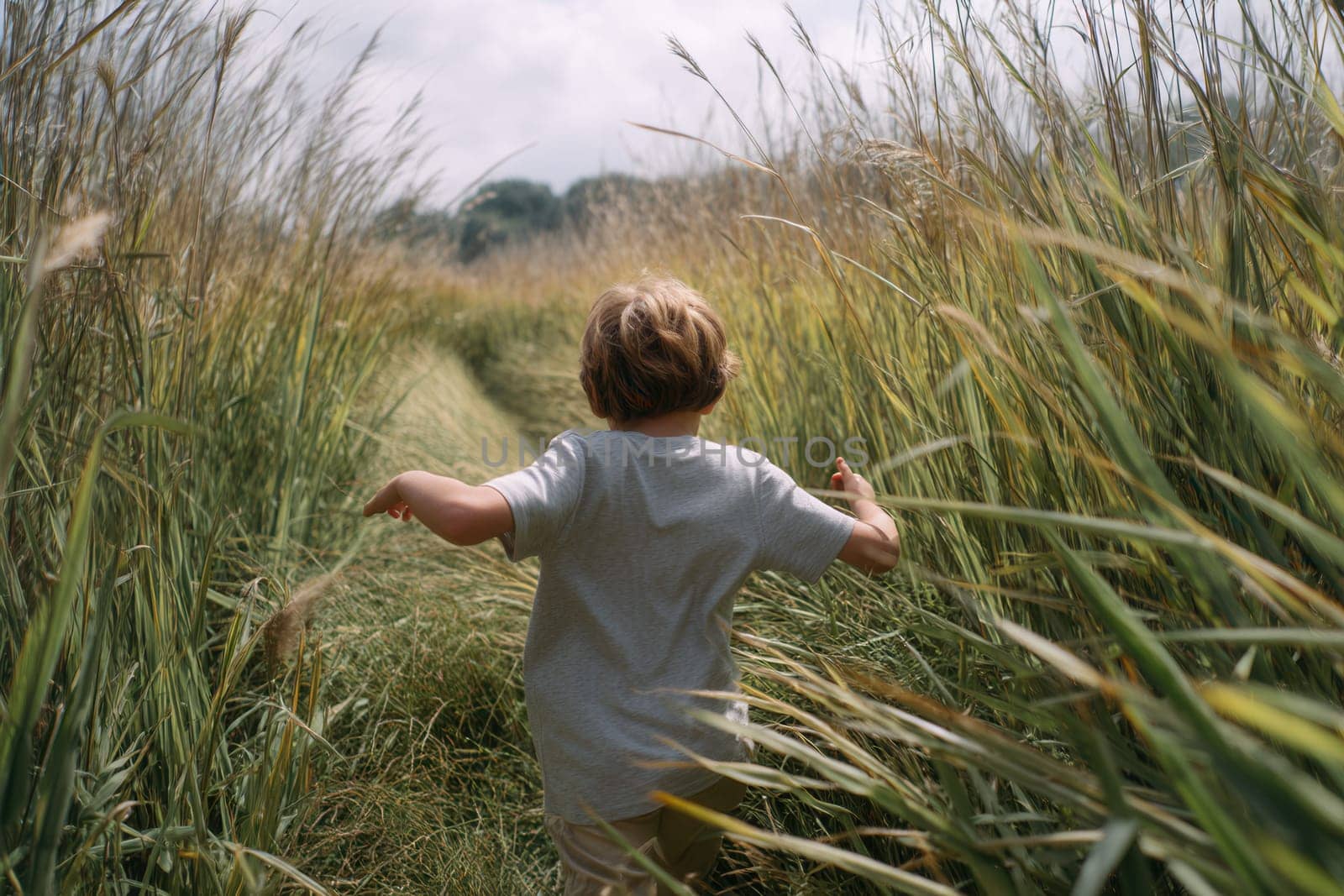 A young boy runs freely through tall green grass on a sunny day, embodying childhood joy and exploration. Ideal for nature themes, outdoor lifestyle, and summer memories