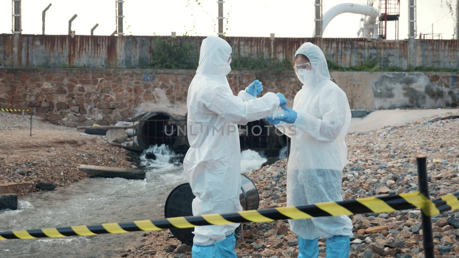 Ecologist sampling water from the river with test tube, Scientist or Biologist in a protective suit and protect mask collects sample of waste water from industrial for analyze, problem environment