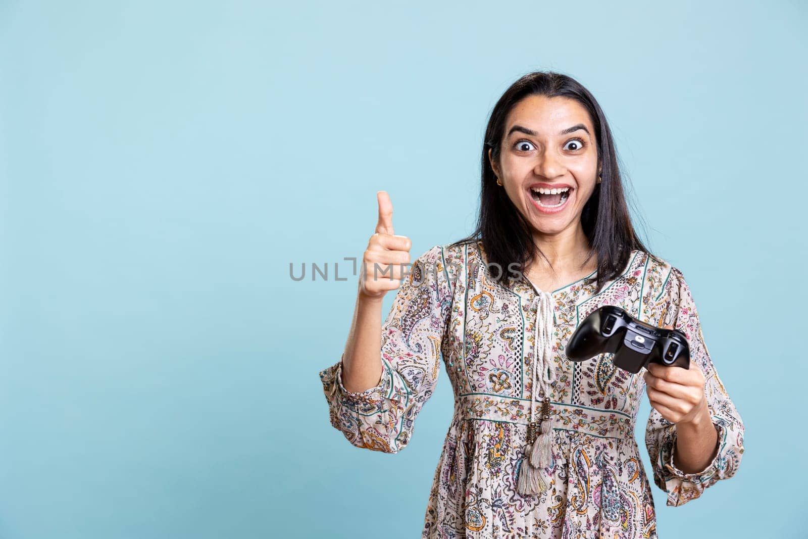 Indian girl winning the video game championship and giving thumbs up, feeling confident and happy with her victory. Ecstatic jolly woman entertained by video games on the console.