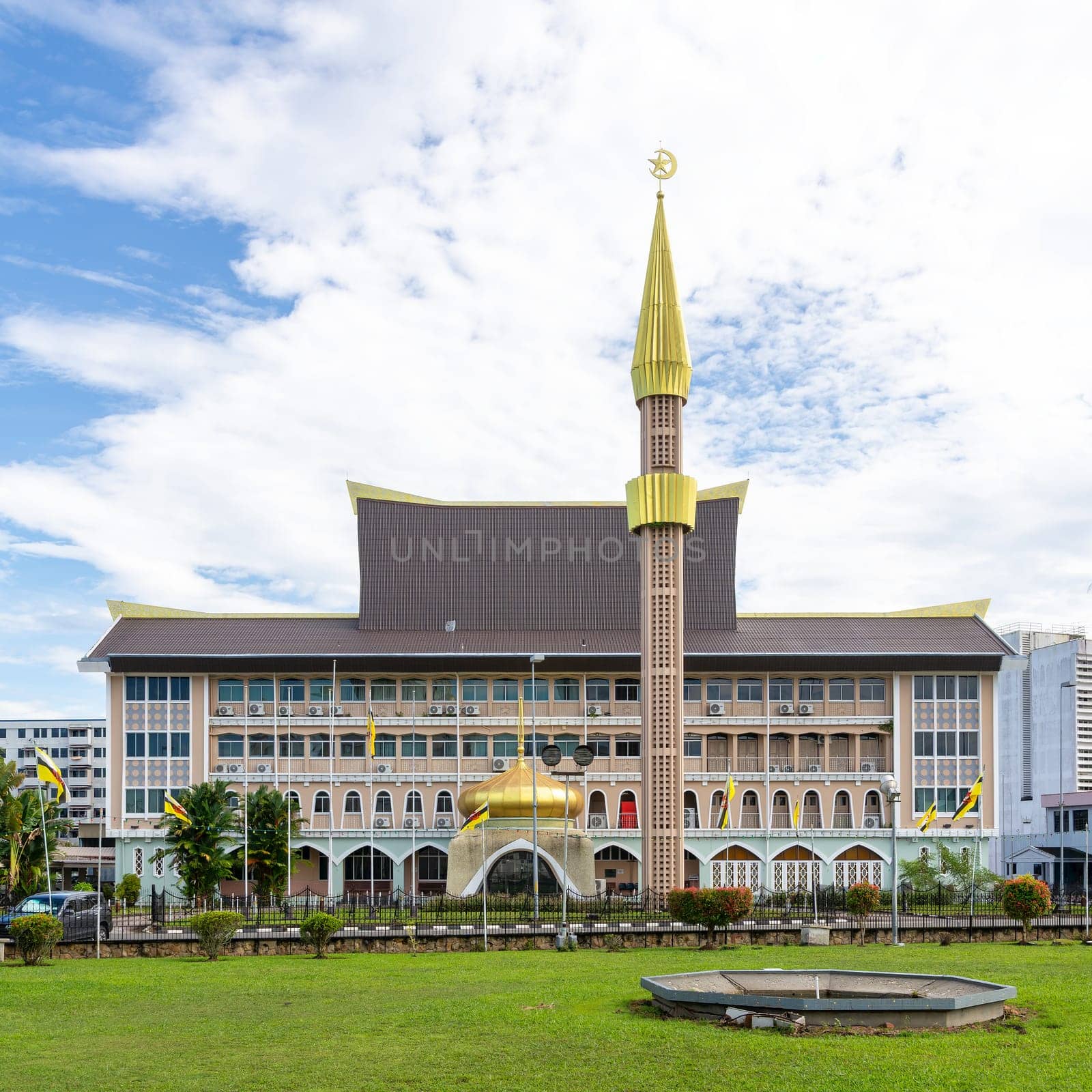 Visitors admire the stunning architecture of the Department of Syariah Affairs building in Bandar Seri Begawan, Brunei, showcasing its golden dome and intricate design under a clear sky