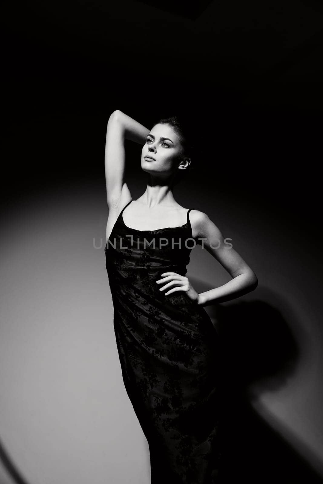 Black and white image of a sophisticated female model striking a pose, embodying elegance and fashion in a minimalist setting. Mood and style concept.