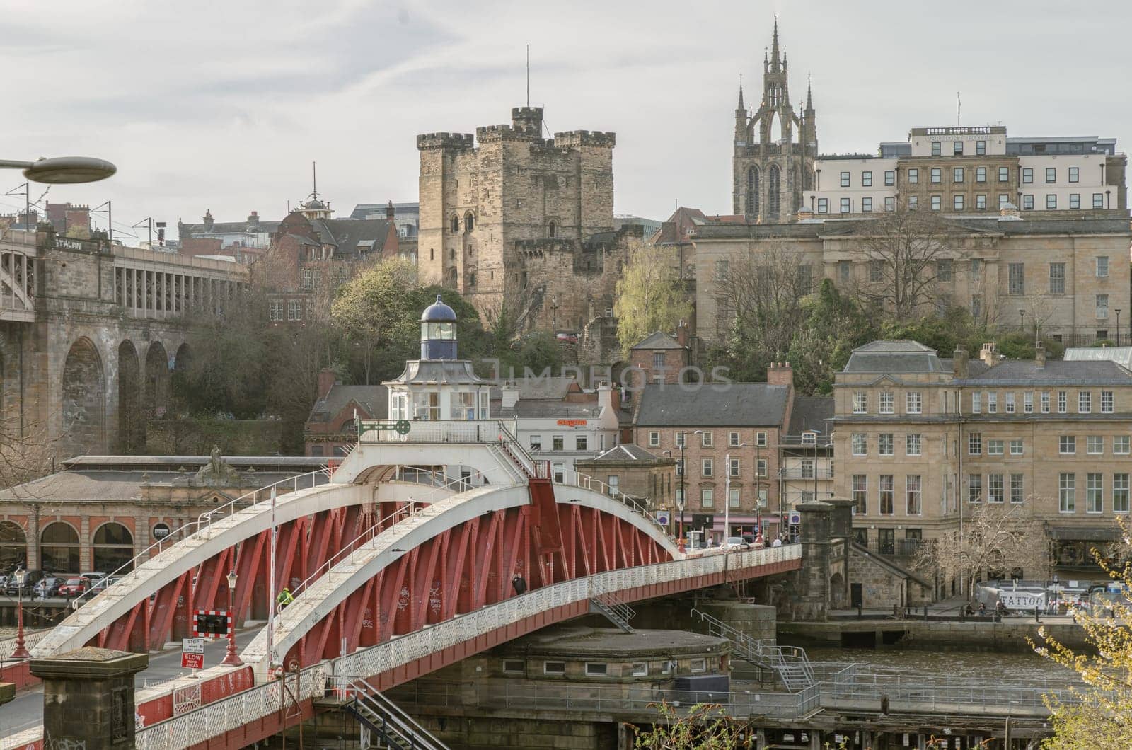 Newcastle, UK - Apr 11, 2025 - A view of The Iconic Swing bridge or Swing span bridge spanning spanning the River Tyne with historical buildings at the background in Newcastle Upon Tyne in the North East of England. The pedestrian bridge, use it as your Wallpaper, Poster and Space for text, Selective focus.
