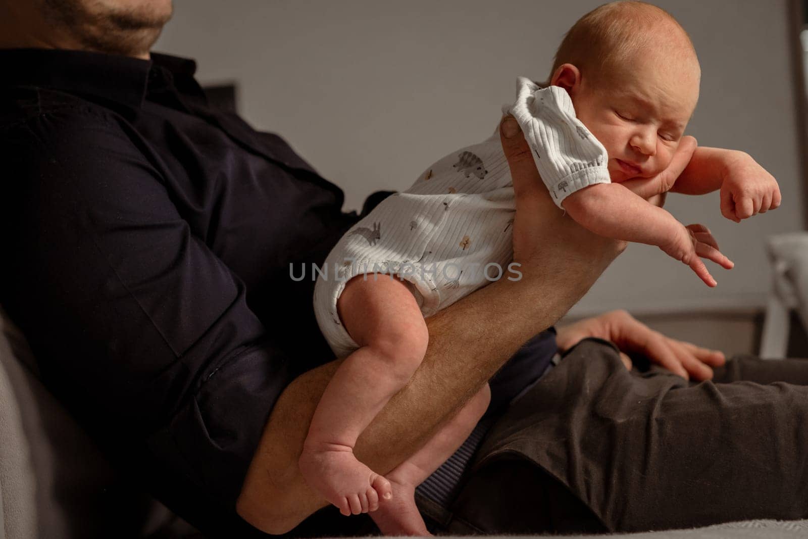 A parent gently holds a newborn baby in a cozy living room, showcasing a tender moment in the warm glow of evening light.