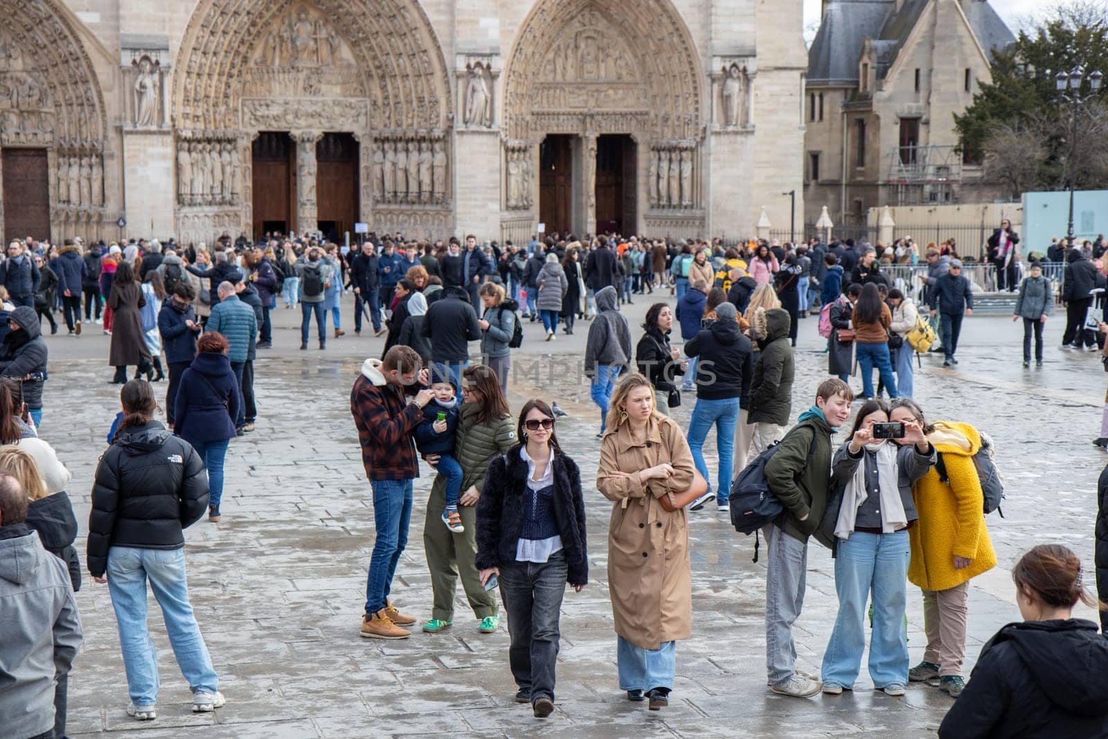Paris, France - February 22nd 2025 : visitors in The Notre-Dame de Paris, newly re-opened cathedral restored after reconstruction, details of exterior
