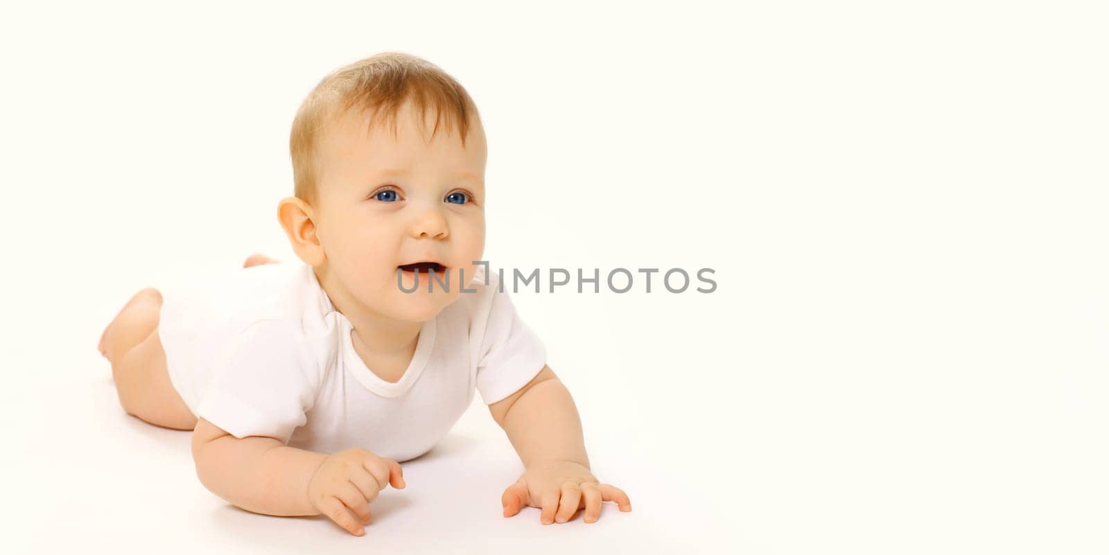 Portrait of happy cute baby crawling on the floor on white studio background
