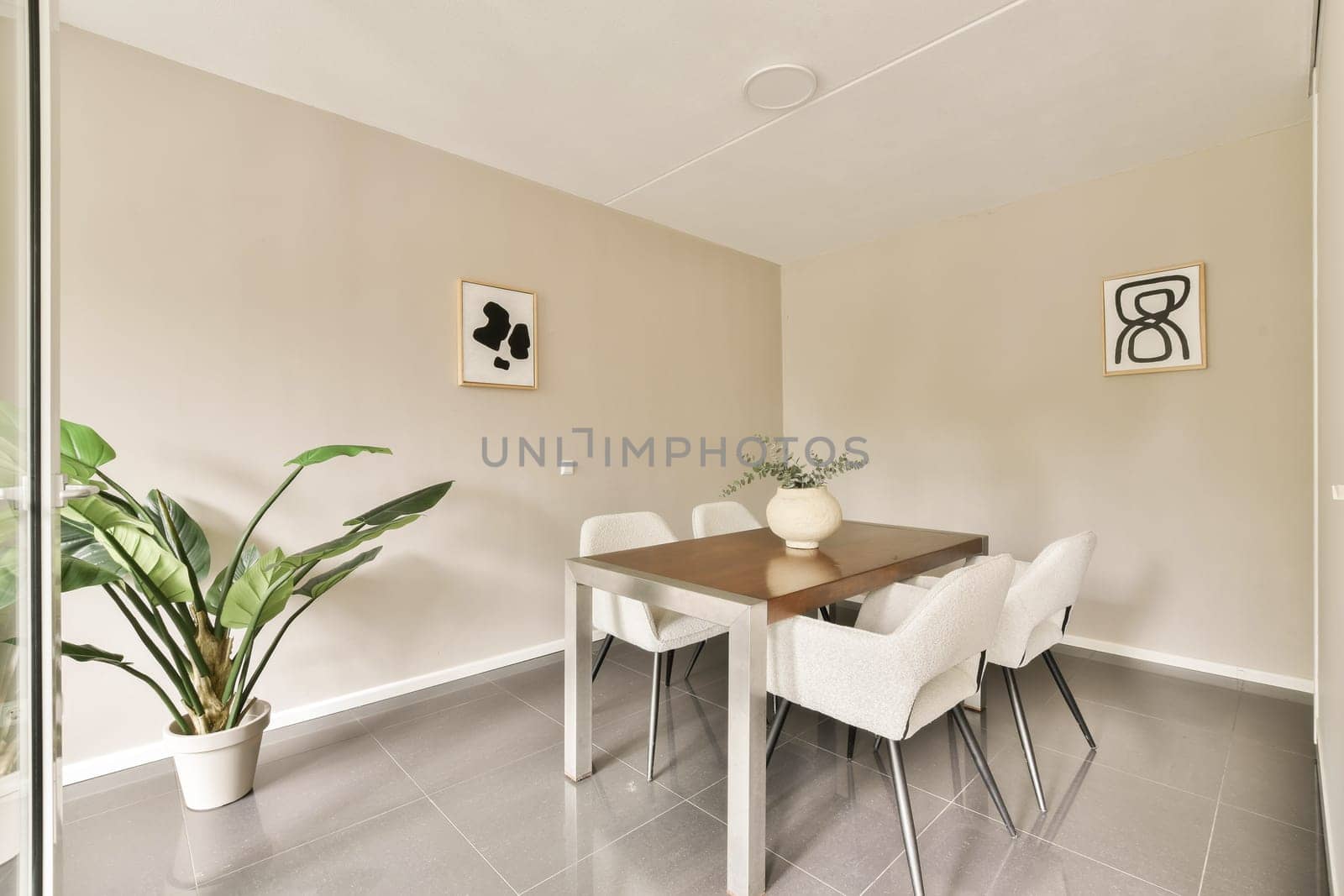 A chic dining area featuring a trendy table, contemporary chairs, decorative wall art, and a plant, creating a warm and inviting ambiance.