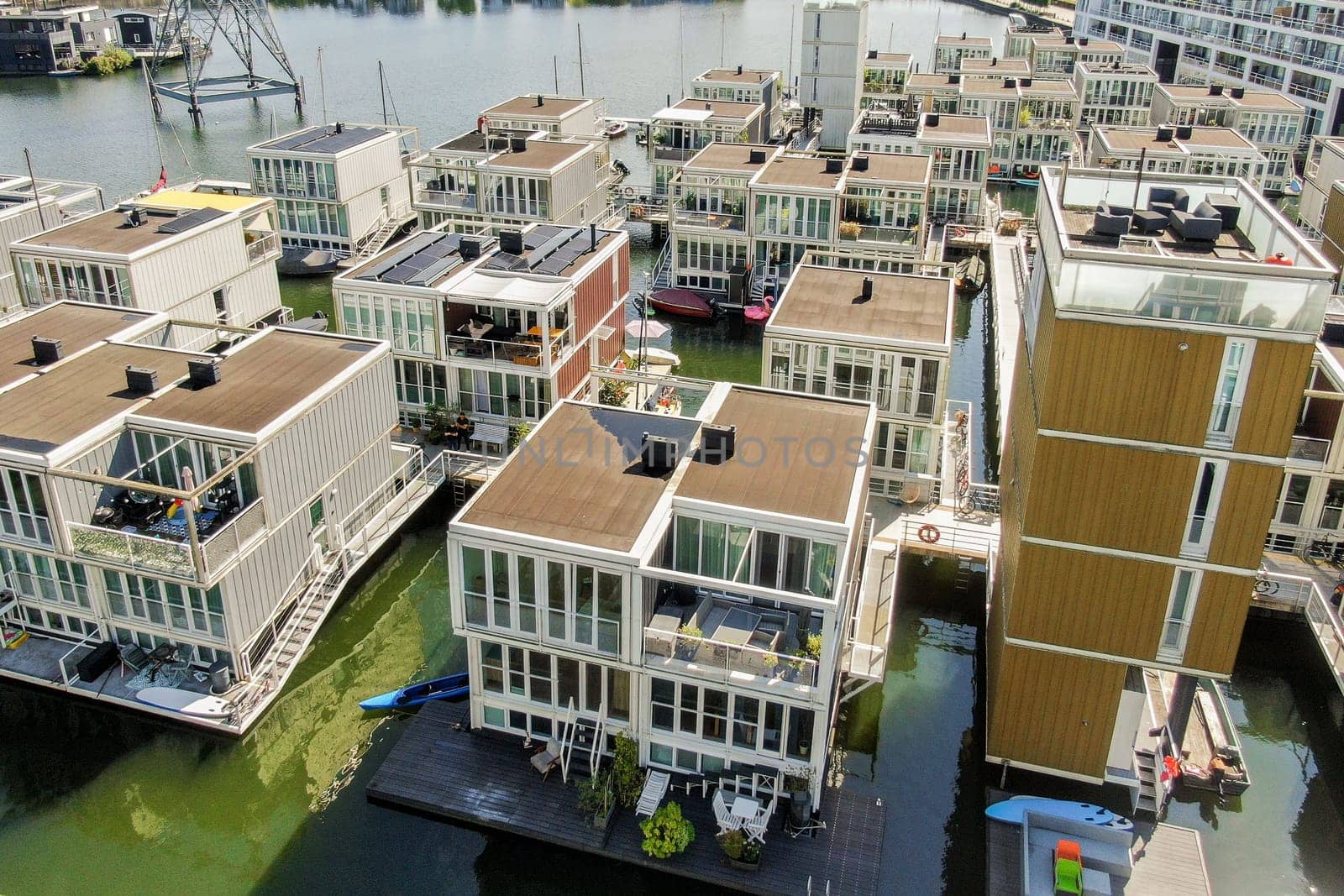 Aerial view of contemporary floating houses arranged near a canal, showcasing innovative architecture and vibrant colors in urban living.