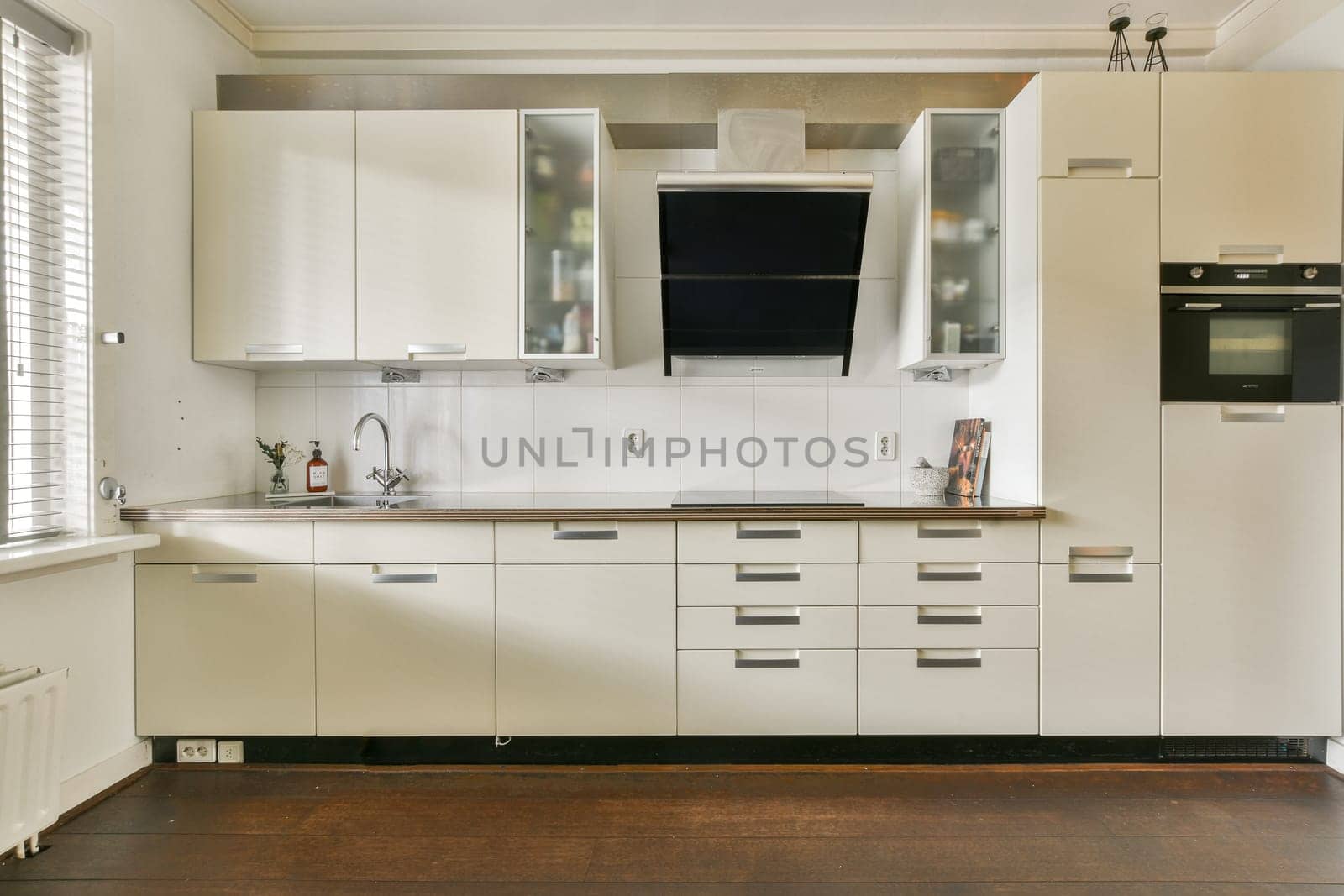 Sleek and contemporary kitchen featuring minimalist white cabinetry, a stylish extractor hood, and an efficient layout perfect for cooking and hosting.