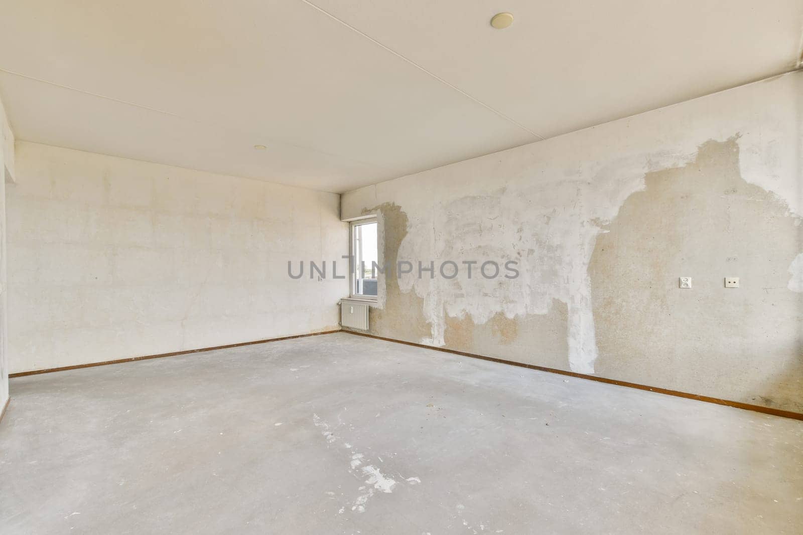 An empty room featuring textured, unfinished walls and a bare floor. Ideal for showcasing interior design potential or renovation concepts.