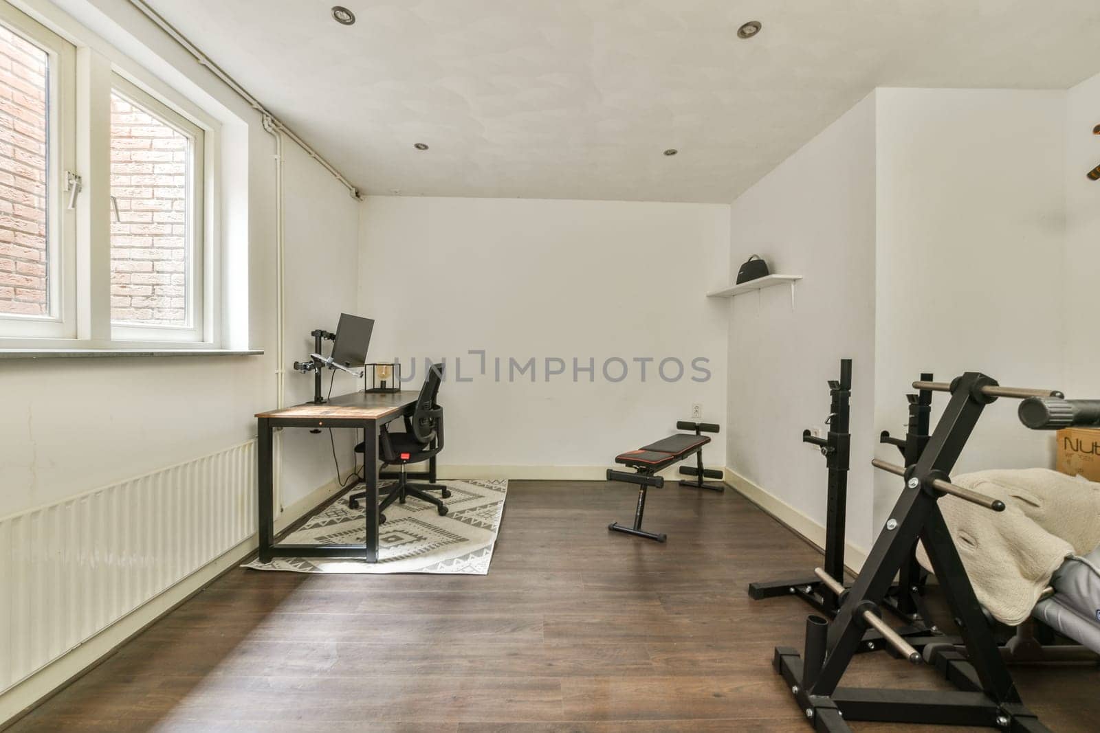 A stylish home office featuring a desk, chair, and exercise equipment in a well-lit room with minimalist decor, ideal for productivity and comfort.