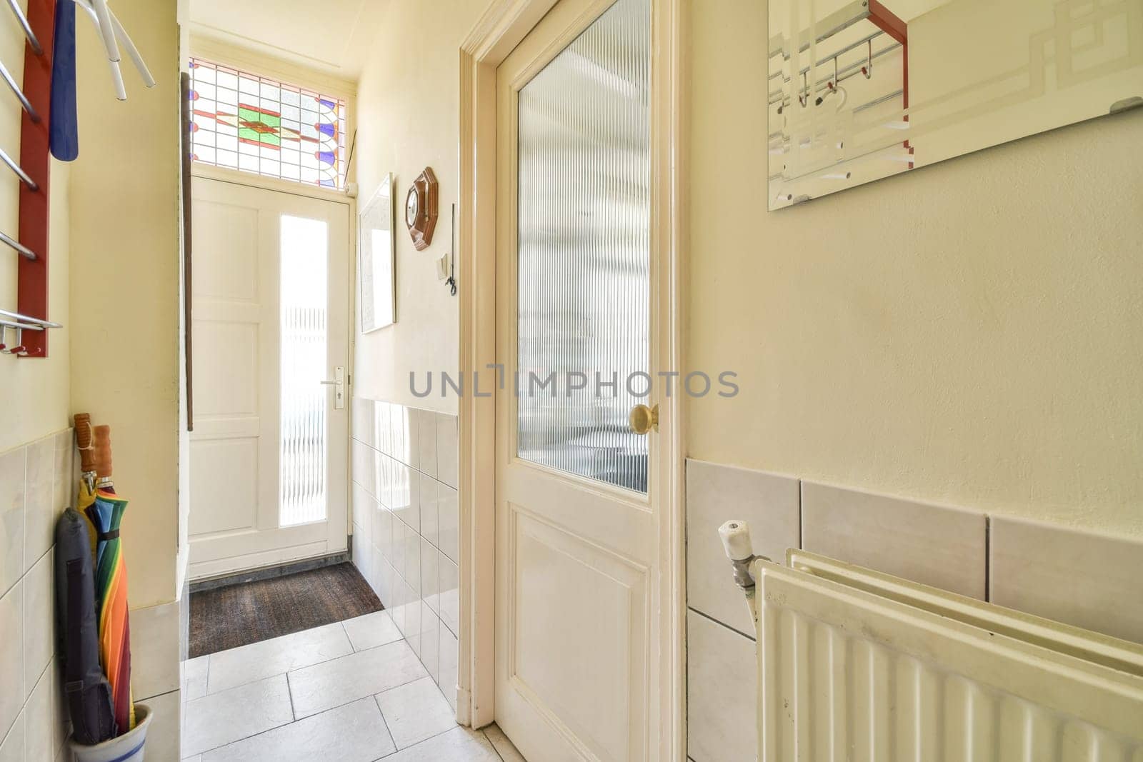 A well-lit entrance hall featuring sleek doors, tiled flooring, and colorful stained glass accents, creating an inviting atmosphere.