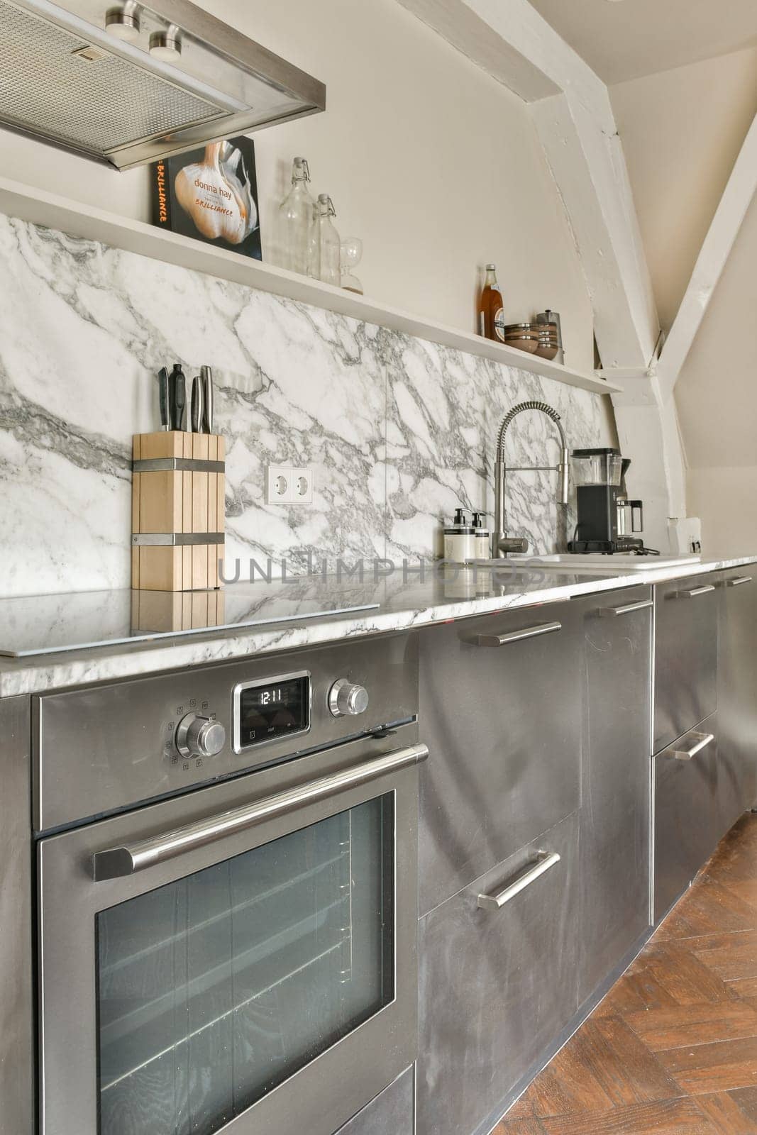 A sleek kitchen featuring elegant marble countertops, stainless steel appliances, and open shelving displaying kitchen essentials. A contemporary design adds to its charm.