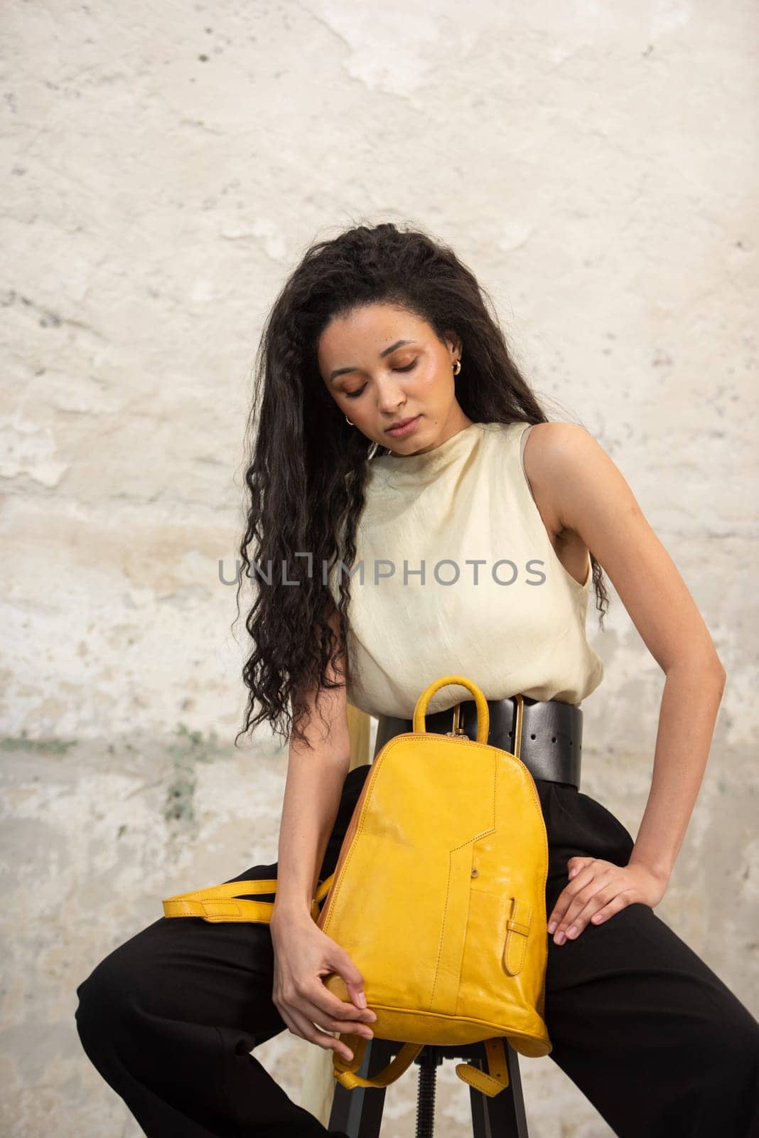 A fashionable model confidently showcasing a modern outfit while sporting a vibrant yellow backpack accessory