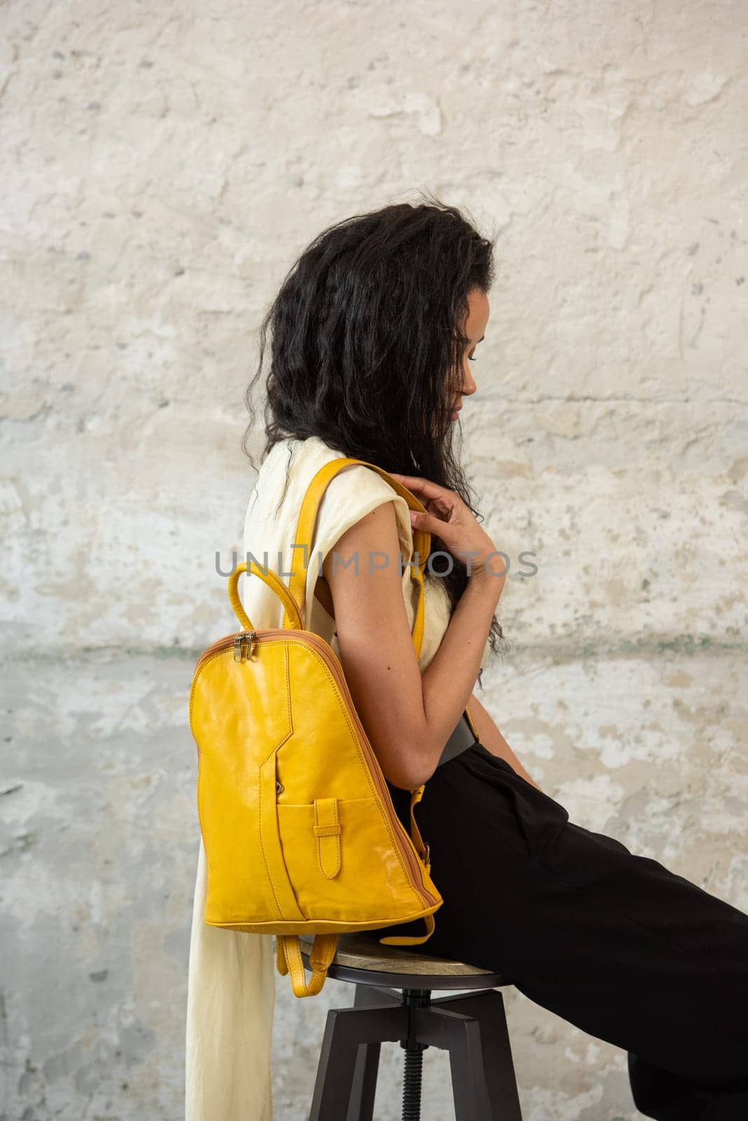 A fashionable model confidently showcasing a modern outfit while sporting a vibrant yellow backpack accessory