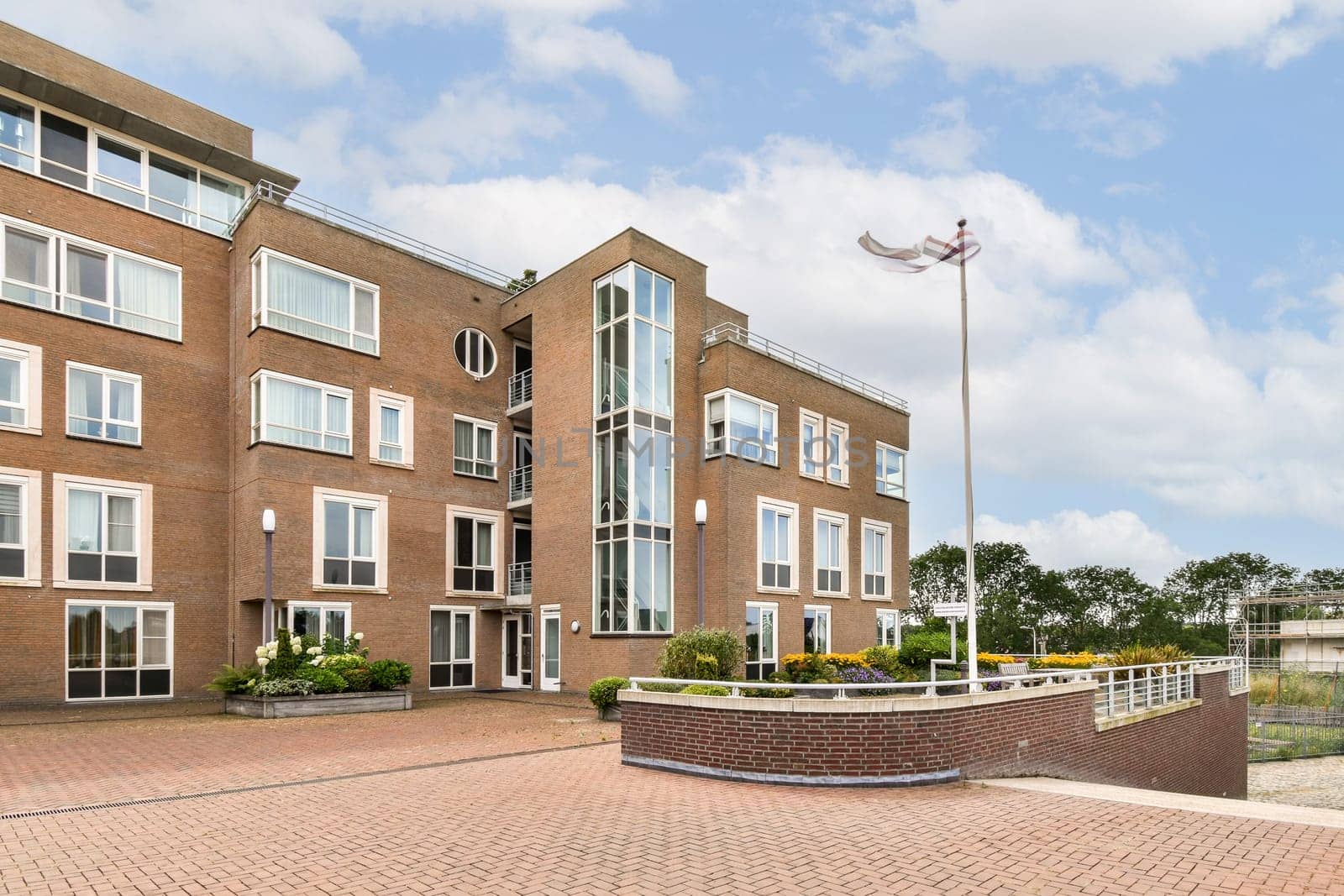 A contemporary brick building featuring large windows, geometric shapes, and landscaped grounds, showcasing modern architectural design.