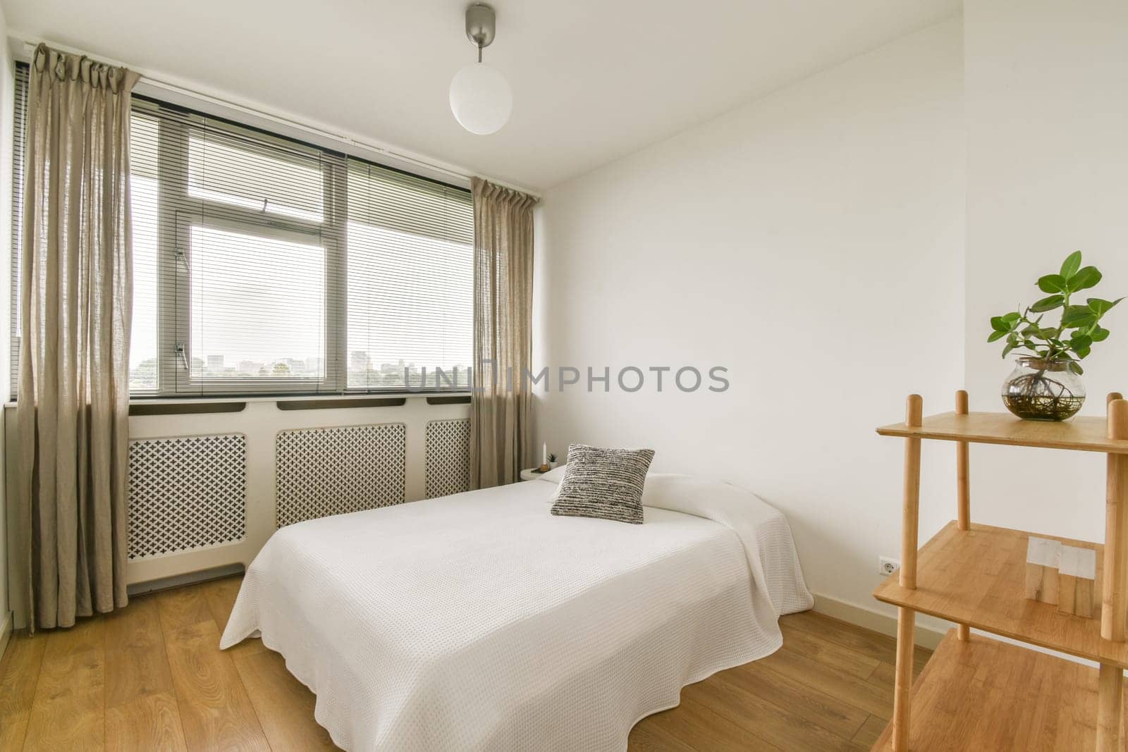 A serene and airy minimalist bedroom featuring a simple bed, wooden accents, and plants, promoting relaxation and comfort.