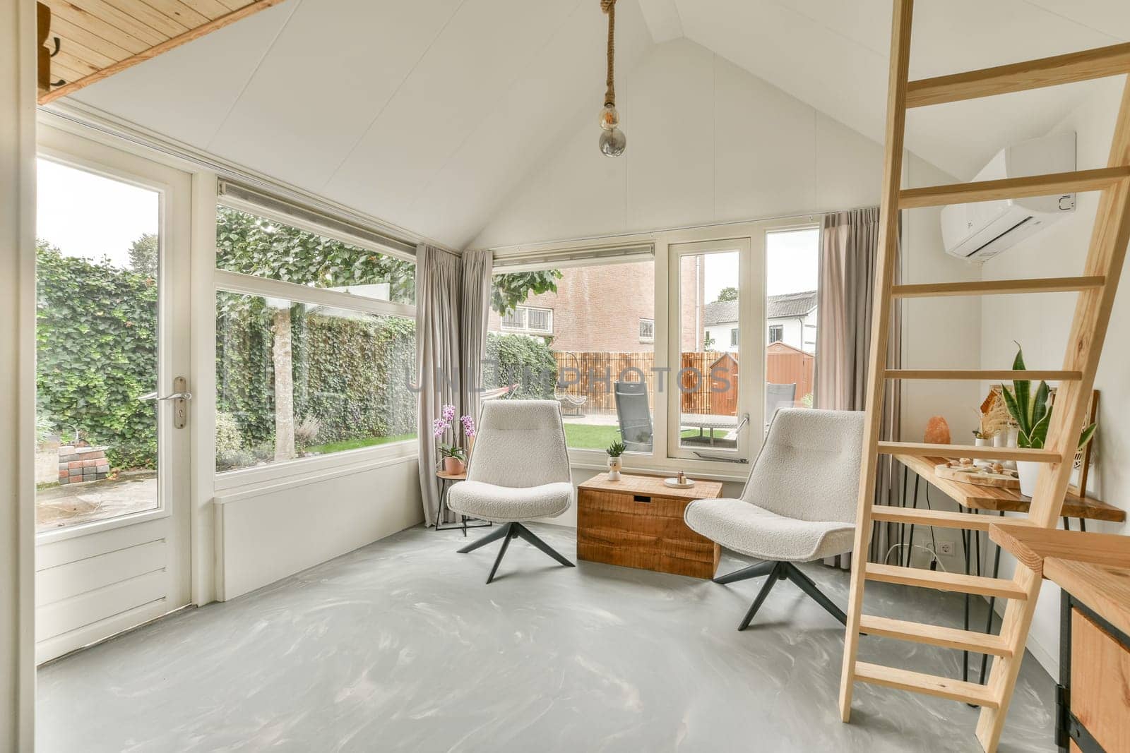 A stylish indoor living space featuring large windows that allow natural light to flood in, complemented by elegant furniture and a serene ambiance.
