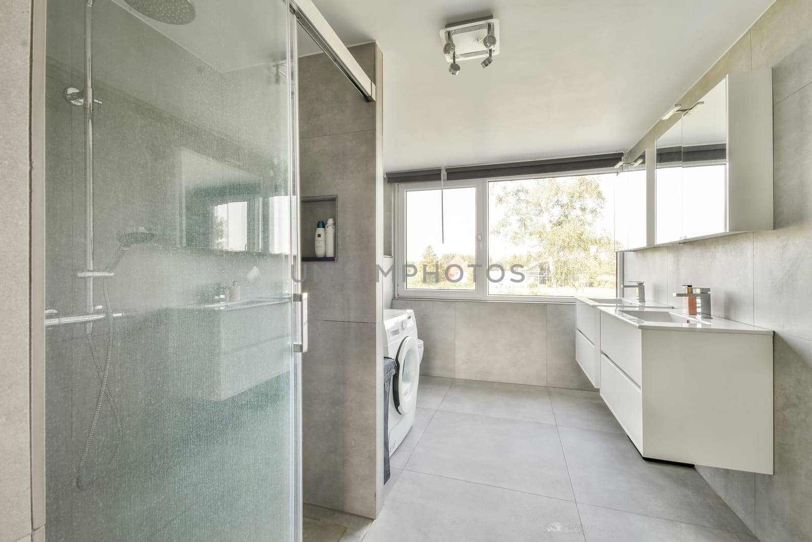 A stylish, modern bathroom featuring a clear glass shower, sleek vanity, and large windows that provide natural light.