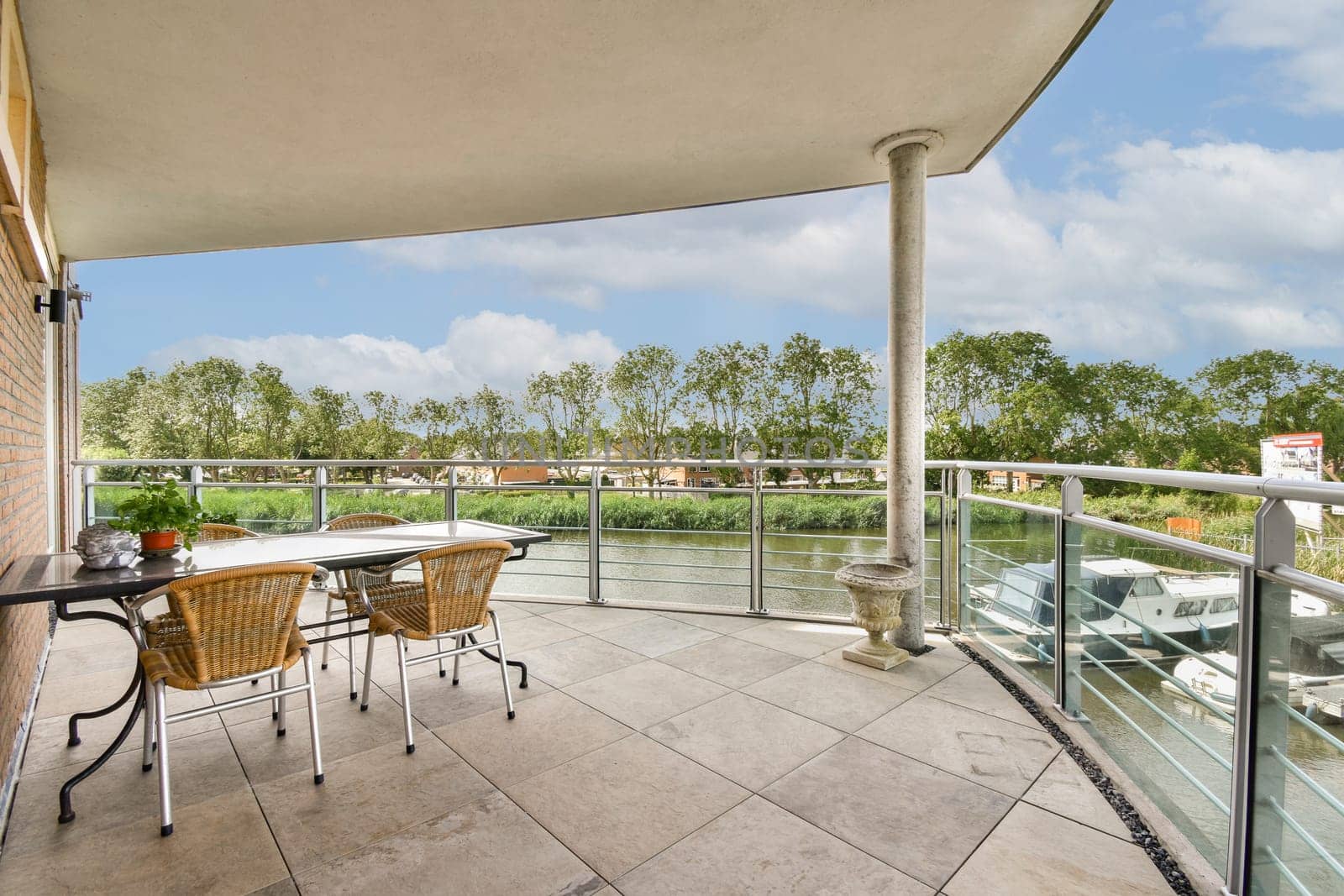 A stylish outdoor patio featuring a dining set with a beautiful view of trees and water, perfect for relaxation and entertaining guests.