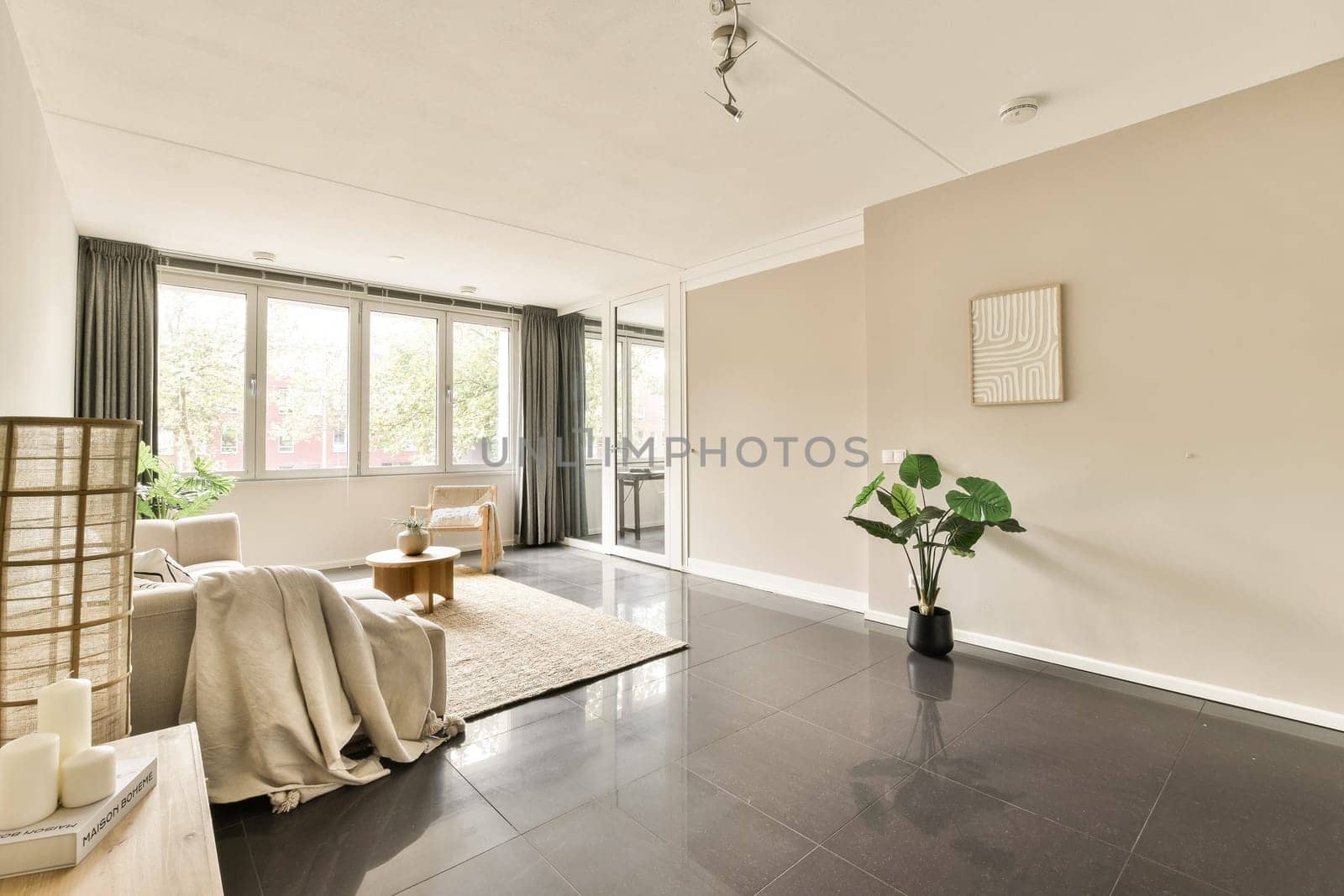 A tranquil modern living room featuring large windows, neutral colors, and minimalistic decor, ideal for relaxation and comfort with natural light flooding in.