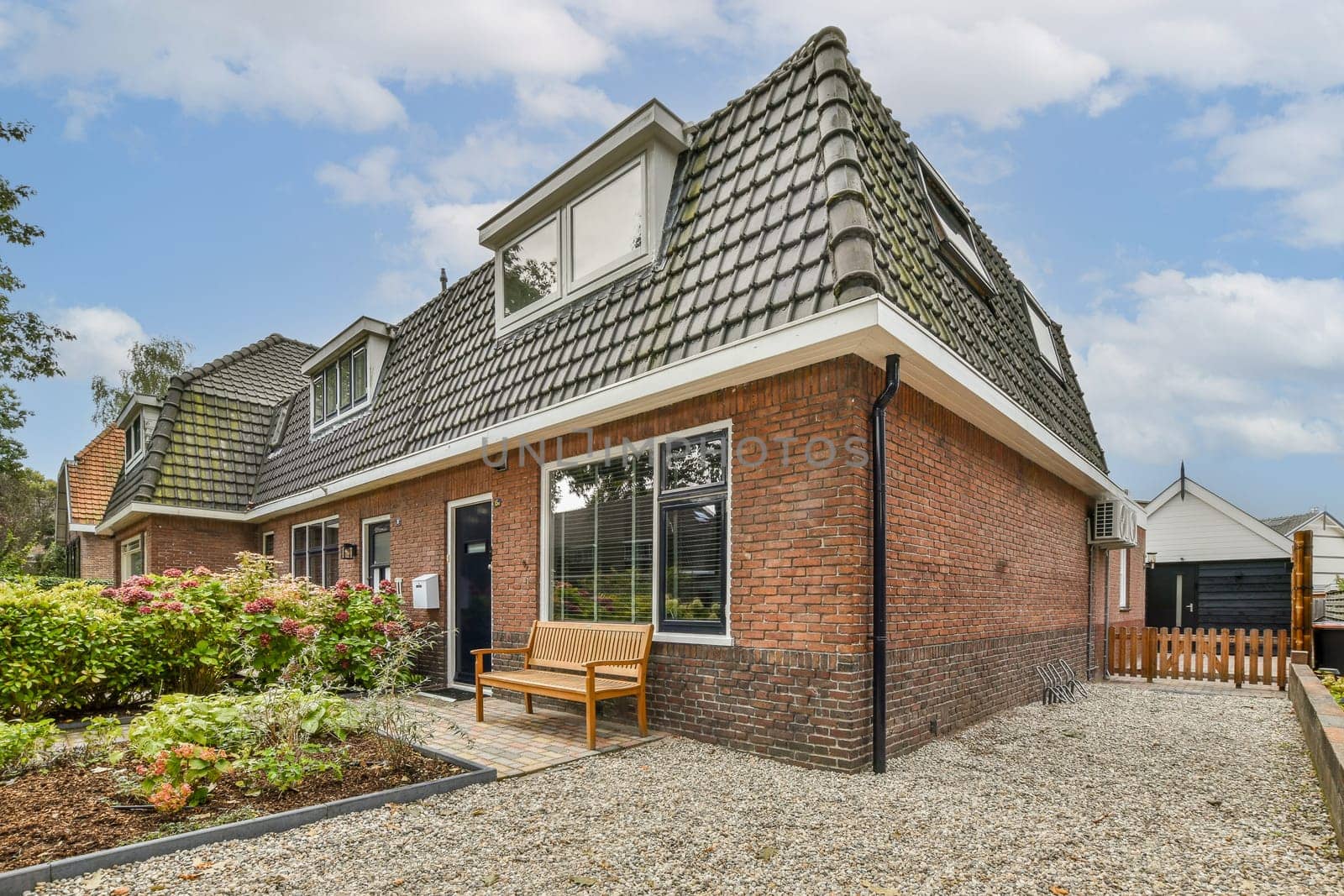 A stylish modern home featuring a unique roof shape, a cozy front garden, and surrounded by greenery, embodying contemporary architectural design.