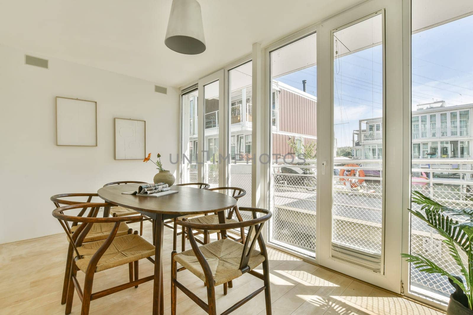 A sleek and airy dining room featuring a round table, stylish chairs, and large windows allowing for abundant natural light. Ideal for contemporary living spaces.