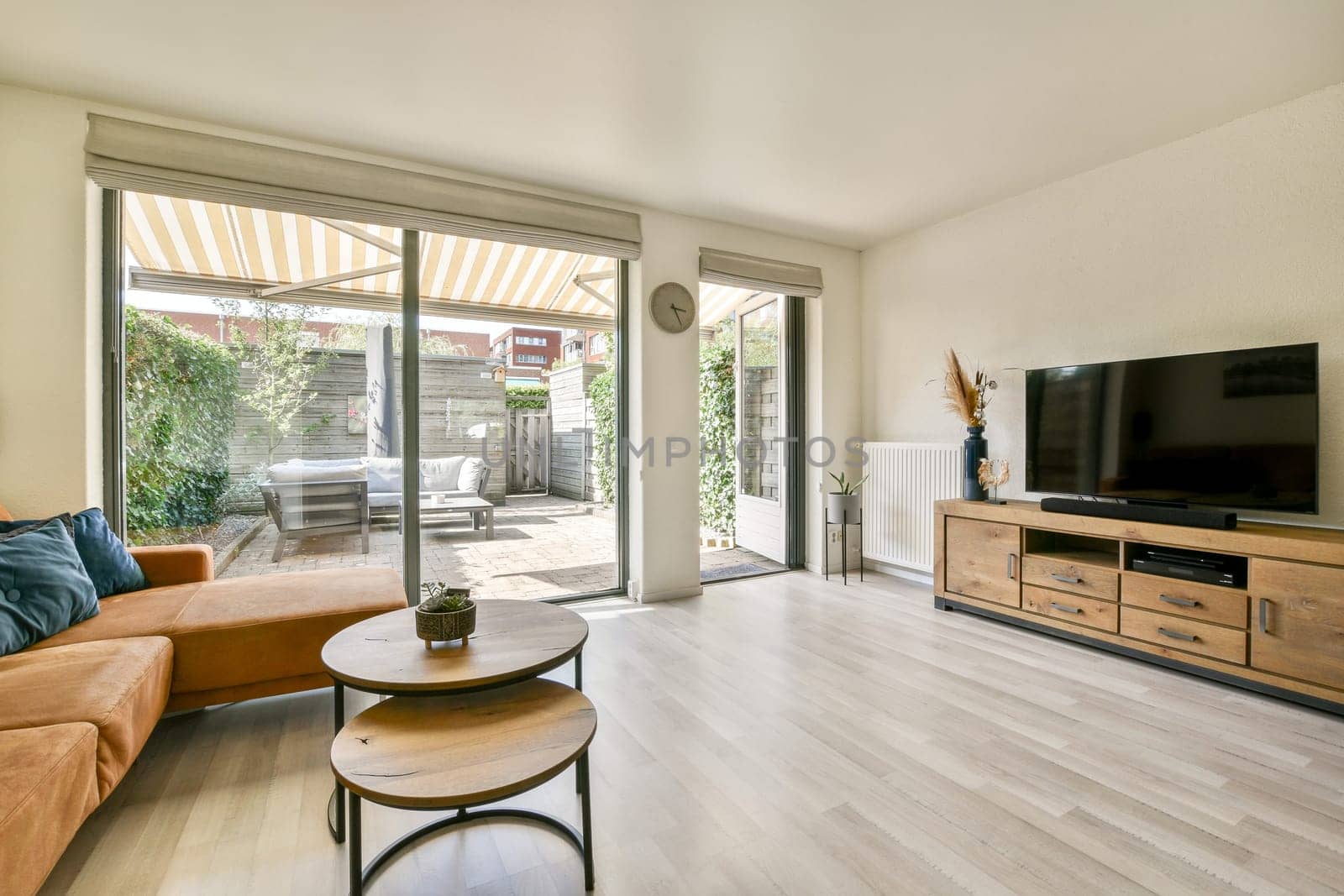 A contemporary living room showcasing natural light through large windows, stylish furniture, and a cozy outdoor area accessible through sliding doors.