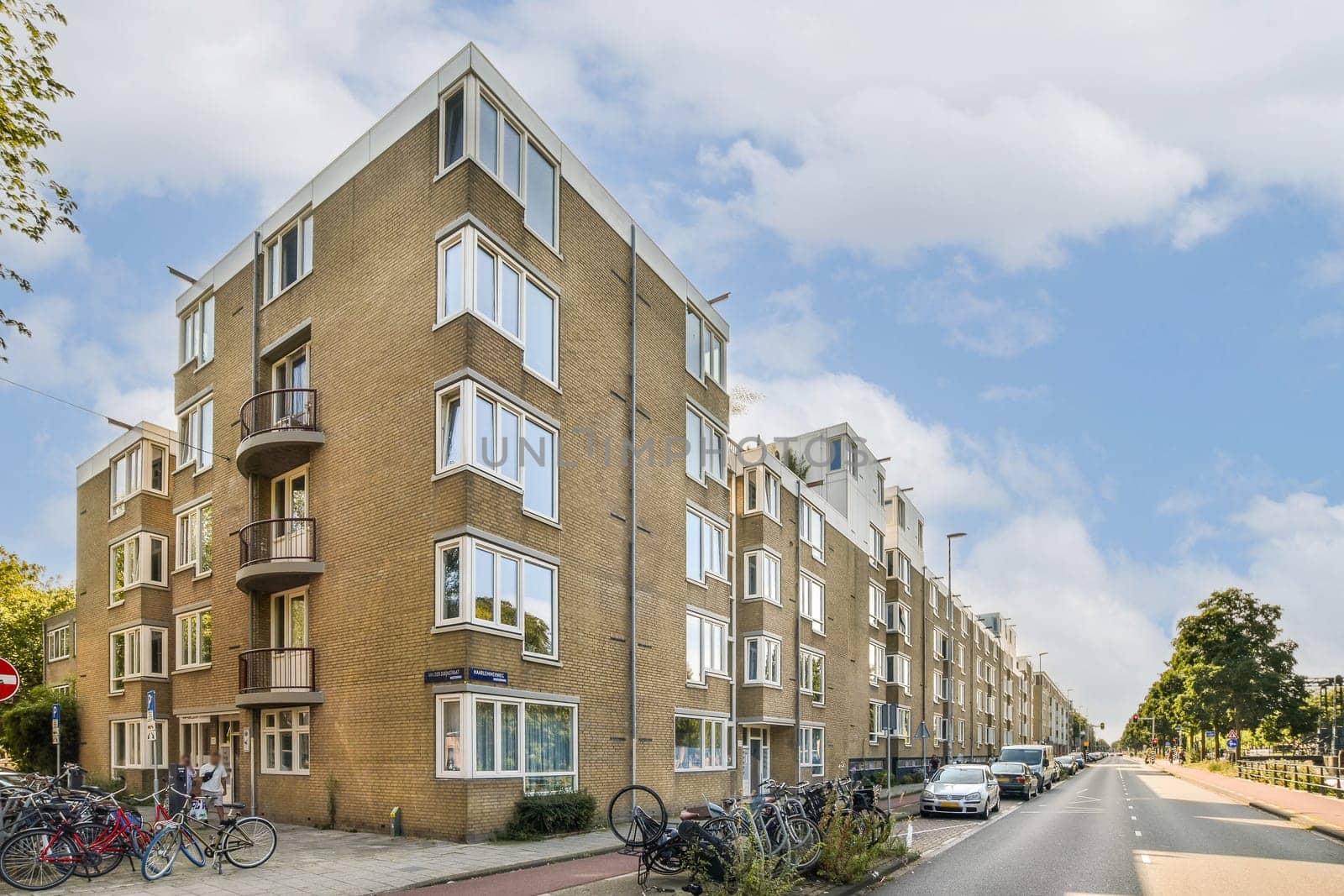 A scenic view of modern residential buildings alongside a cycling path, surrounded by parked bicycles and greenery.