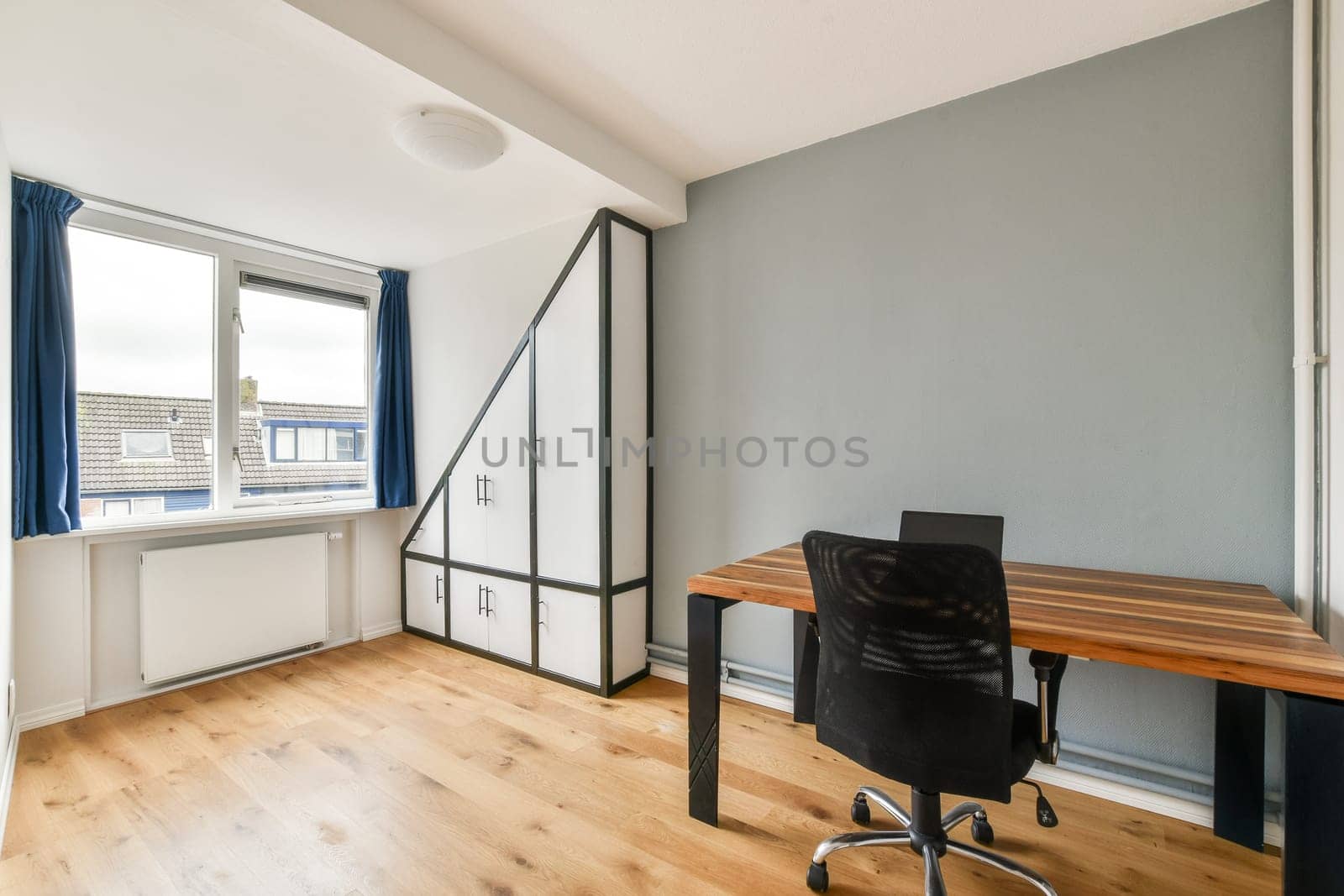 A modern and minimalist home office featuring a desk, chair, and large windows that provide natural light, enhancing the workspace ambiance.