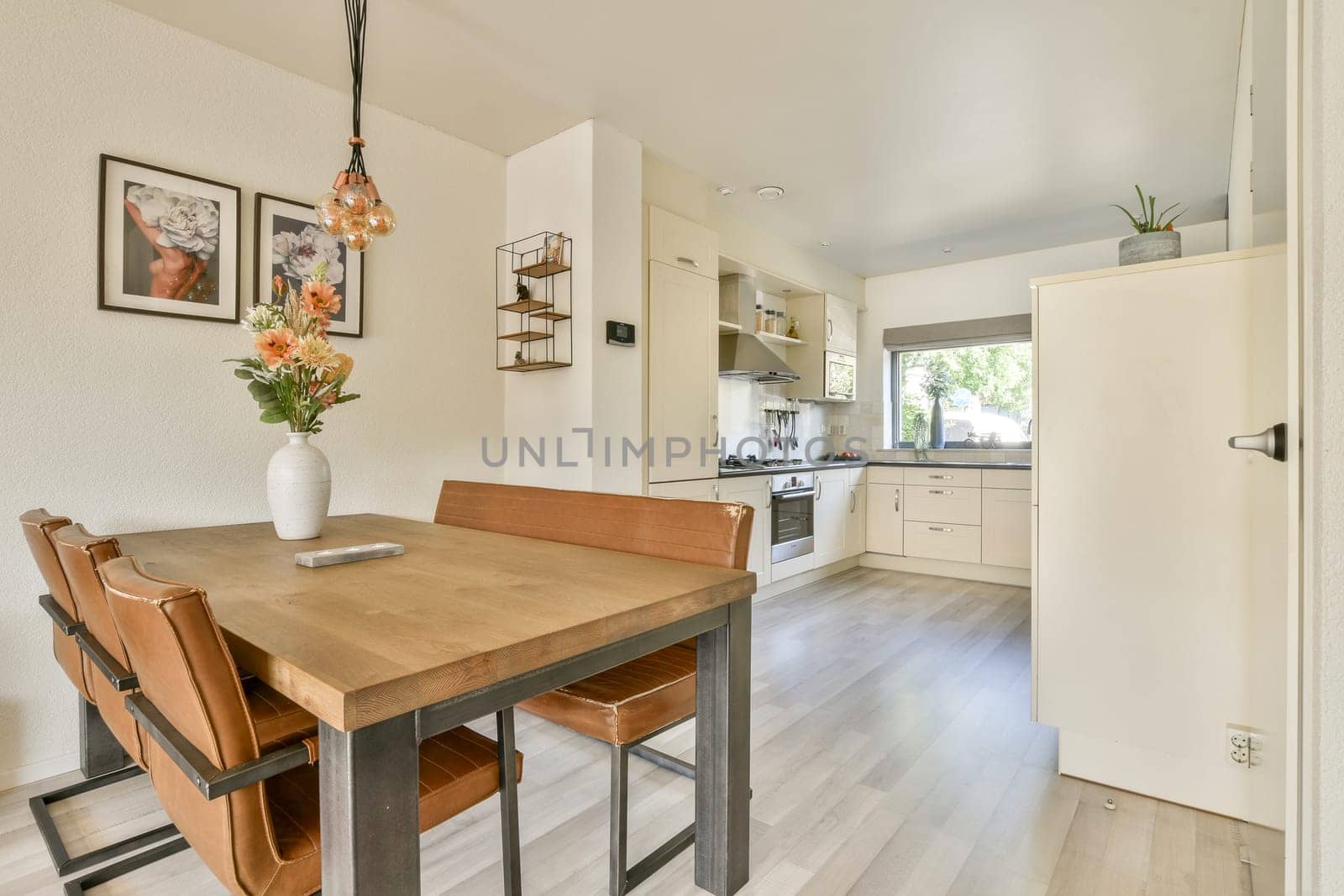 A stylish kitchen interior featuring a dining table with chairs, modern appliances, and decor that creates a welcoming space for meals and gatherings.