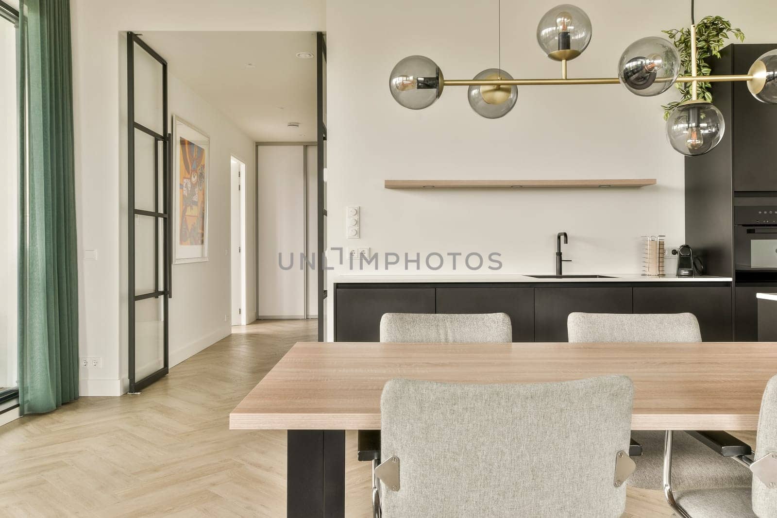 A sleek and contemporary kitchen featuring a stylish dining area with a wooden table, elegant lighting fixtures, and a modern aesthetic.