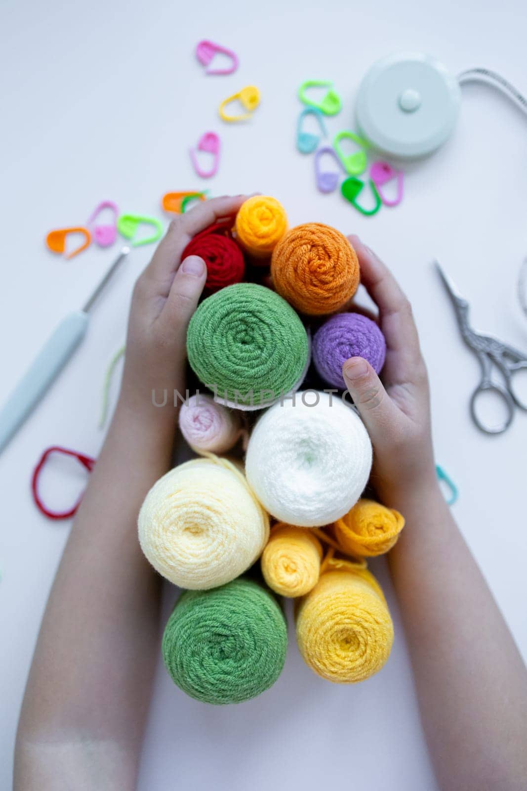 Child hands hold colorful yarn in creative crafting activity.