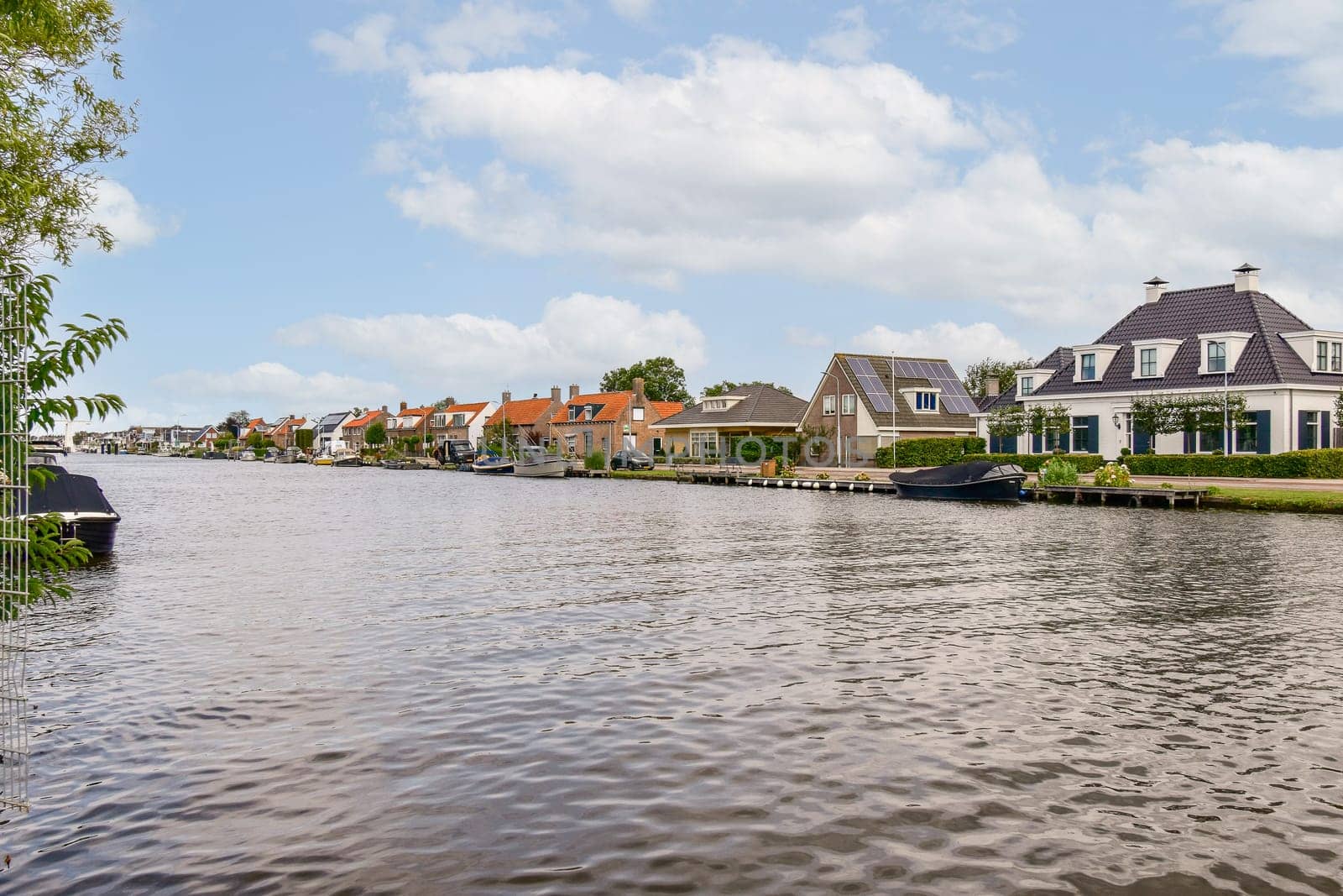 Charming houses line a serene waterway, reflecting a tranquil suburban lifestyle amid lush greenery and clear blue skies.