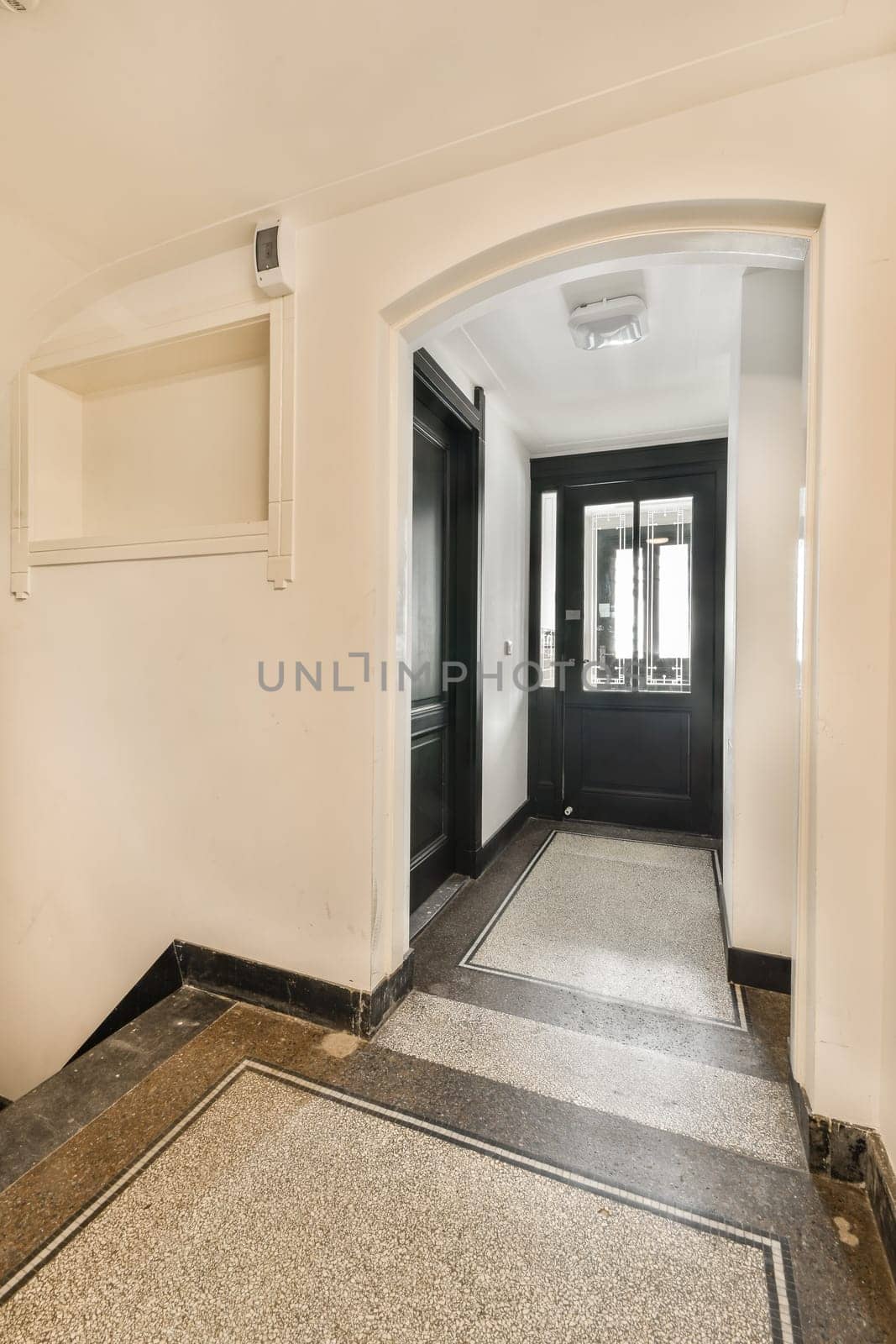 A stylish indoor entrance featuring sleek black doors and polished flooring, creating a sophisticated entryway atmosphere.