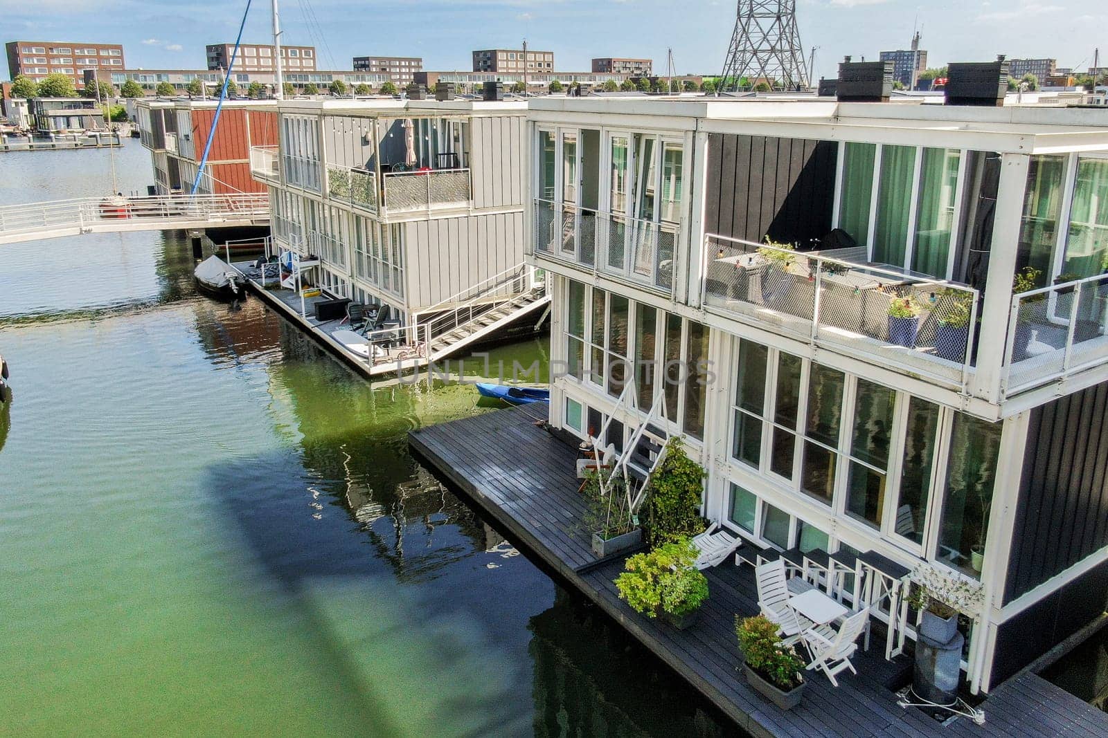 A scenic view featuring contemporary floating houses along a waterfront, showcasing sleek architecture and outdoor living spaces amid a vibrant environment.
