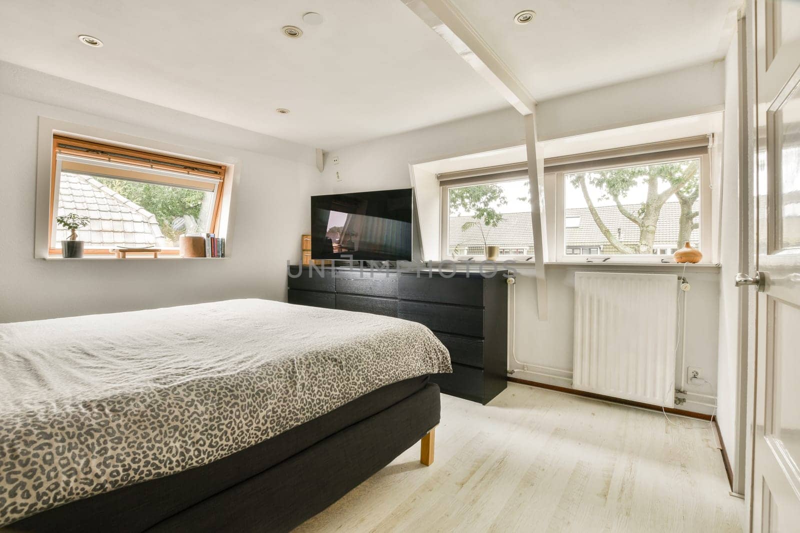 A bright and inviting modern bedroom featuring large windows that let in natural light, a stylish bed, and contemporary furniture.