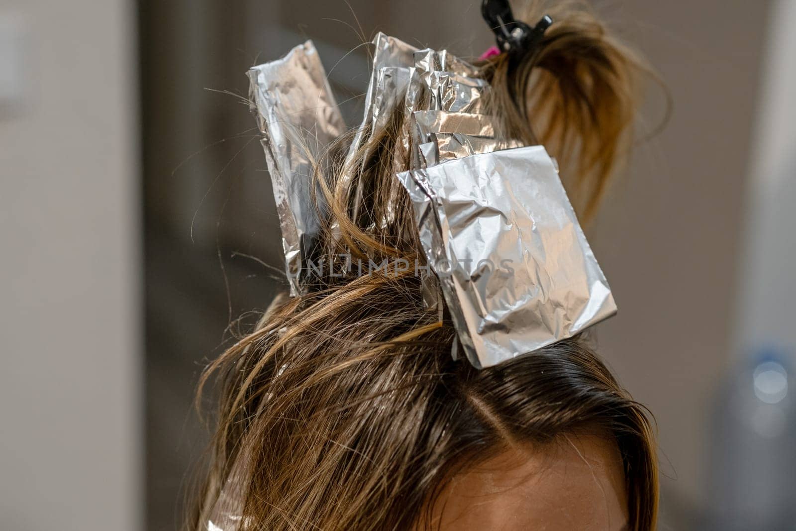 Hair coloring process is underway with foils in place for highlights, showcasing a creative transformation in progress.