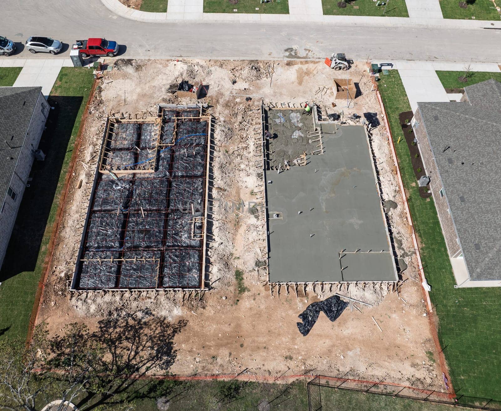 Overhead view of two construction sites, one with a concrete slab and the other a framed foundation ready for concrete