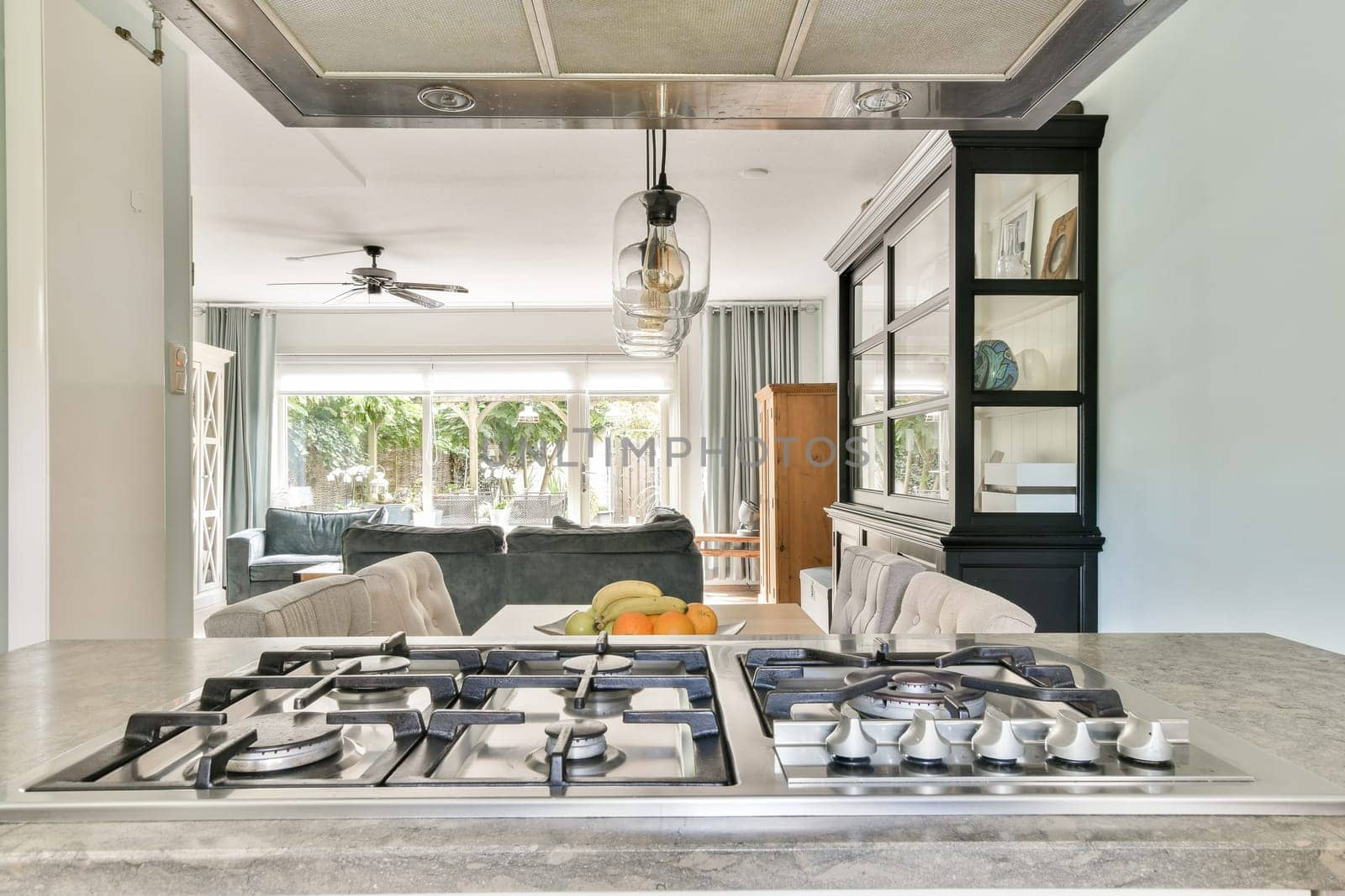 An inviting modern kitchen featuring a sleek gas stove, elegant cabinetry, and a spacious open layout that connects to a bright living area filled with natural light.