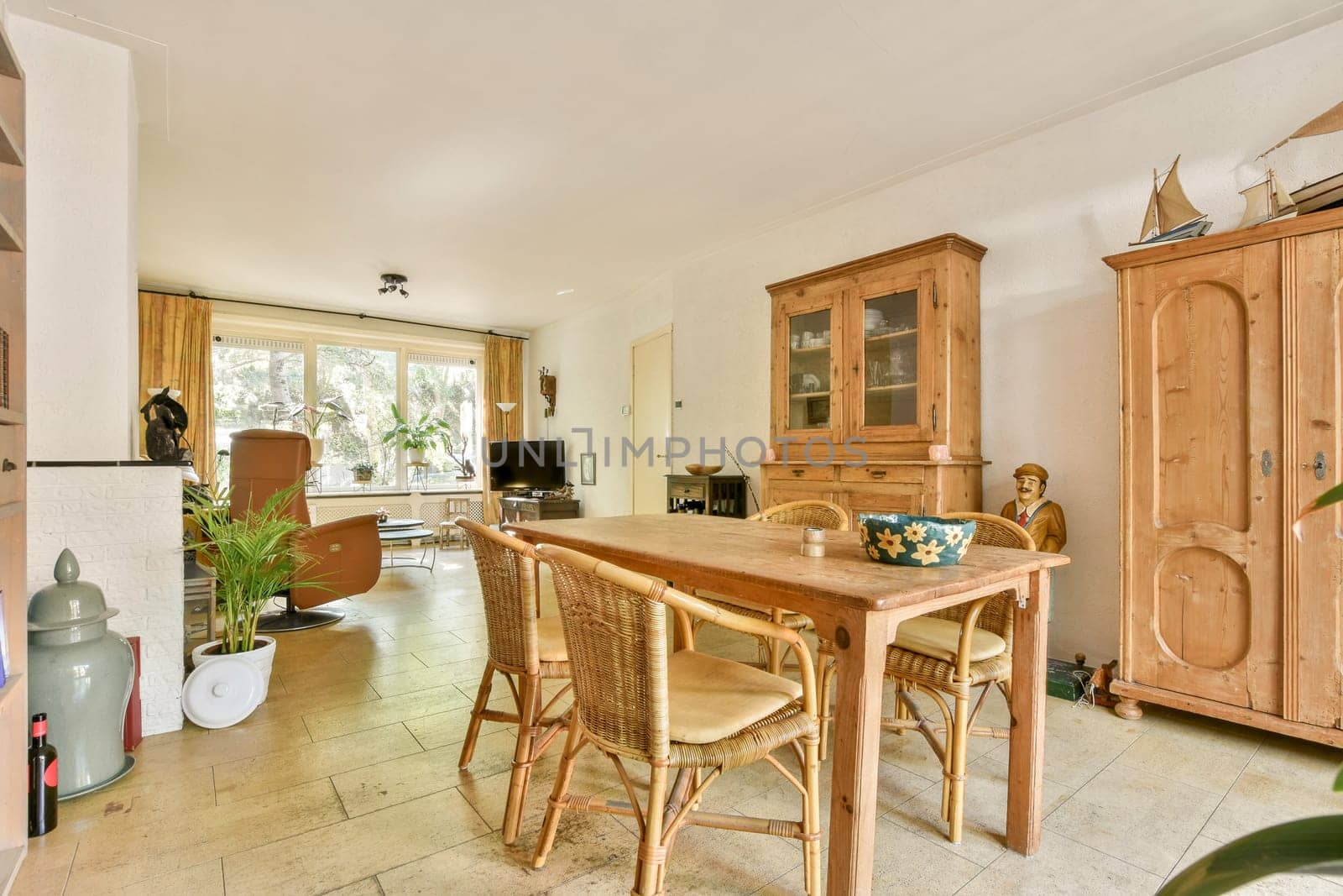 A charming dining area featuring a wooden table surrounded by woven chairs, with warm lighting and wooden cabinetry that enhances the inviting atmosphere.