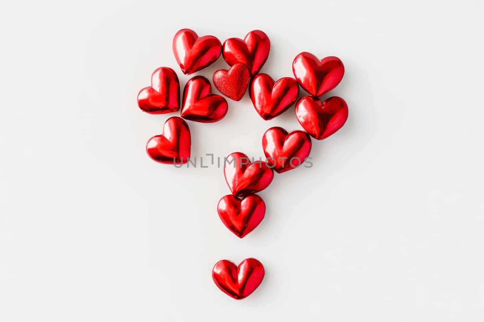 A whimsical composition features numerous shiny red hearts arranged in the shape of a question mark, sparking intrigue and emotion.