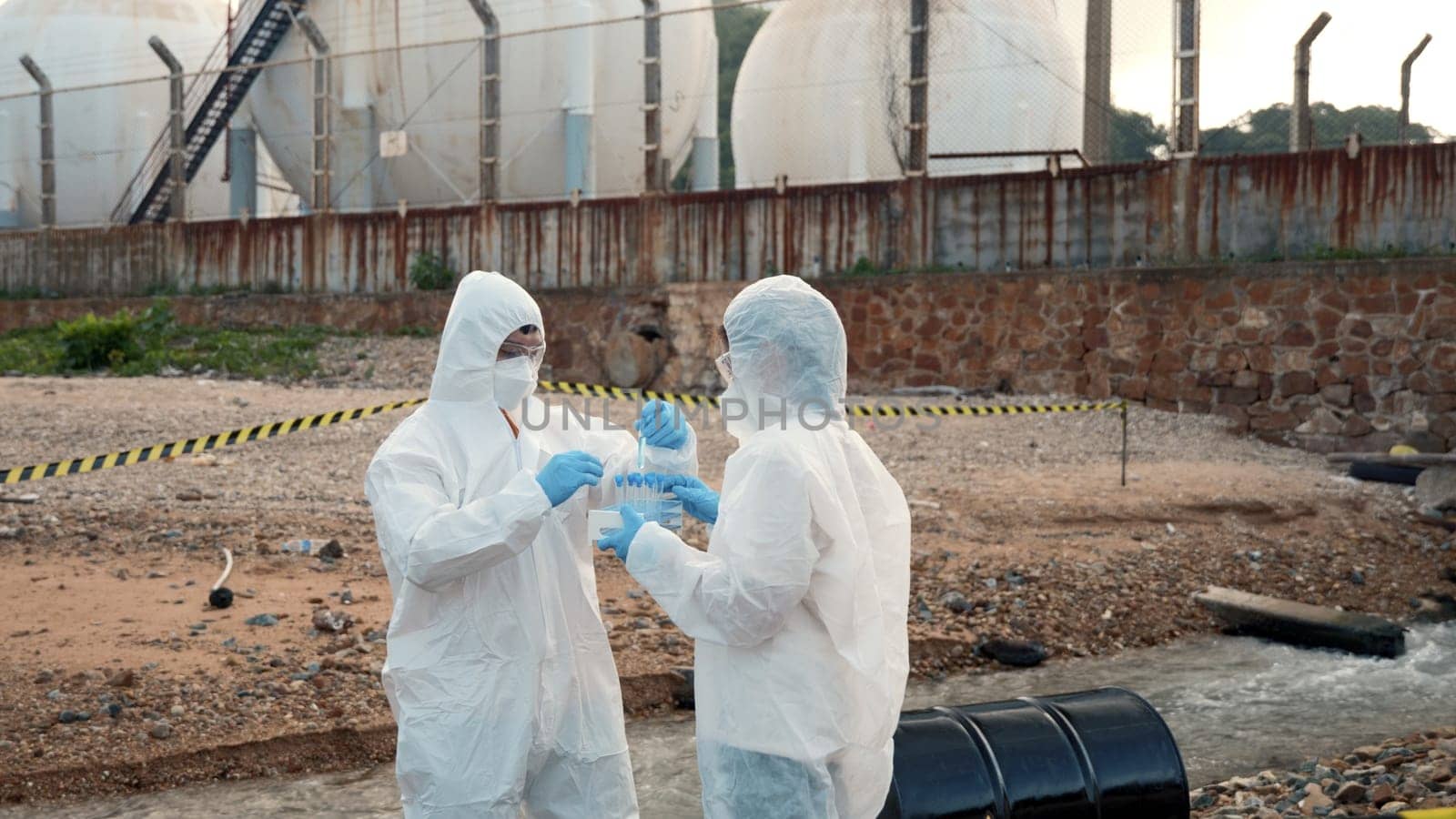 Ecologist sampling water from the river with test tube, Scientist or Biologist in a protective suit and protect mask collects sample of waste water from industrial for analyze, problem environment
