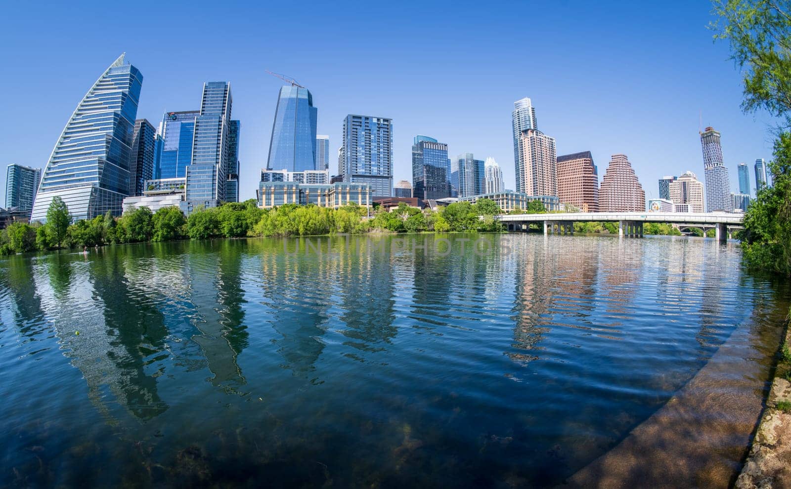 Austin, TX - 10 April 2025:Skyline of the downtown district with fisheye lens with calm waters on Colorado river in spring